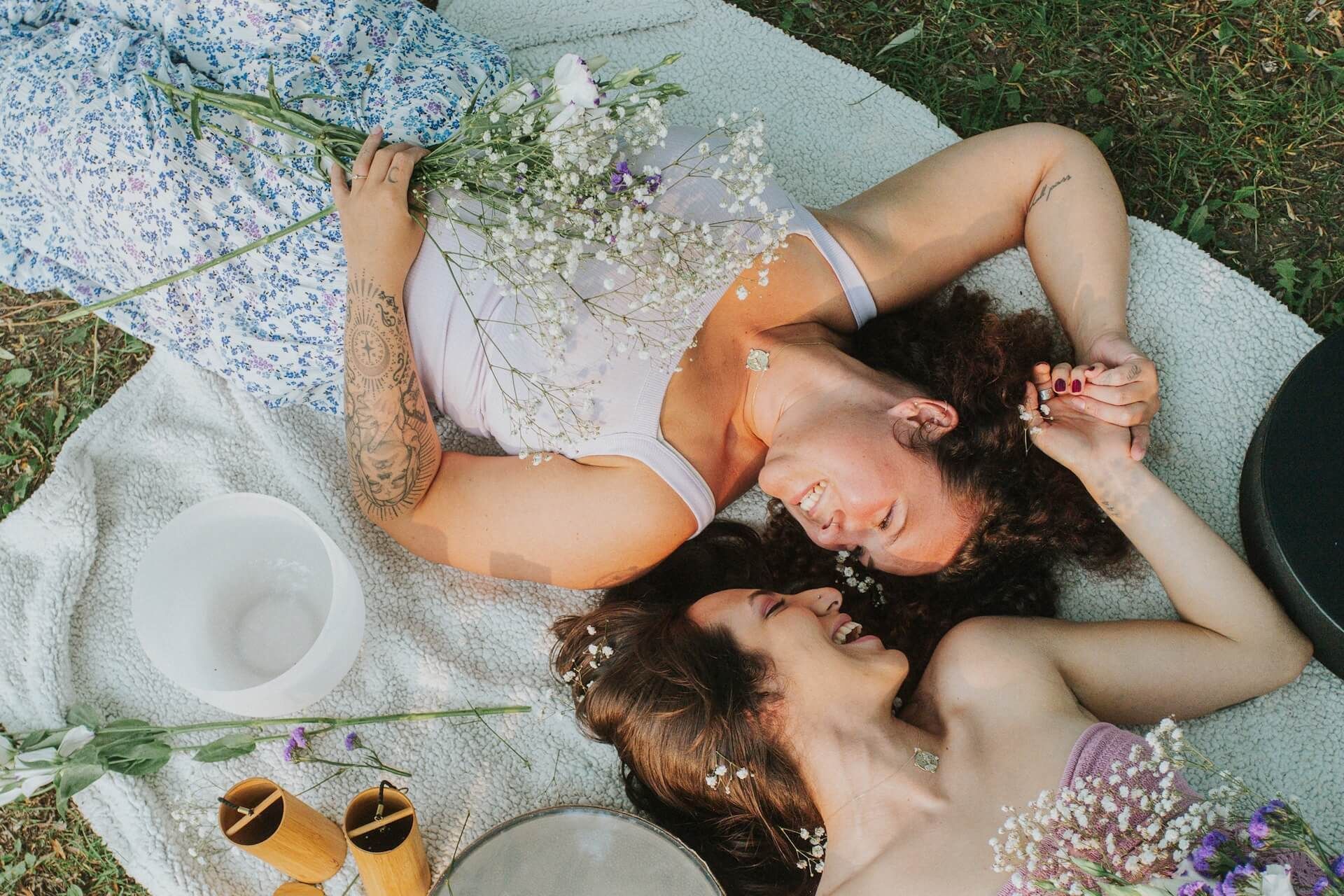 Two women with eyes closed, heads touching, outdoors.