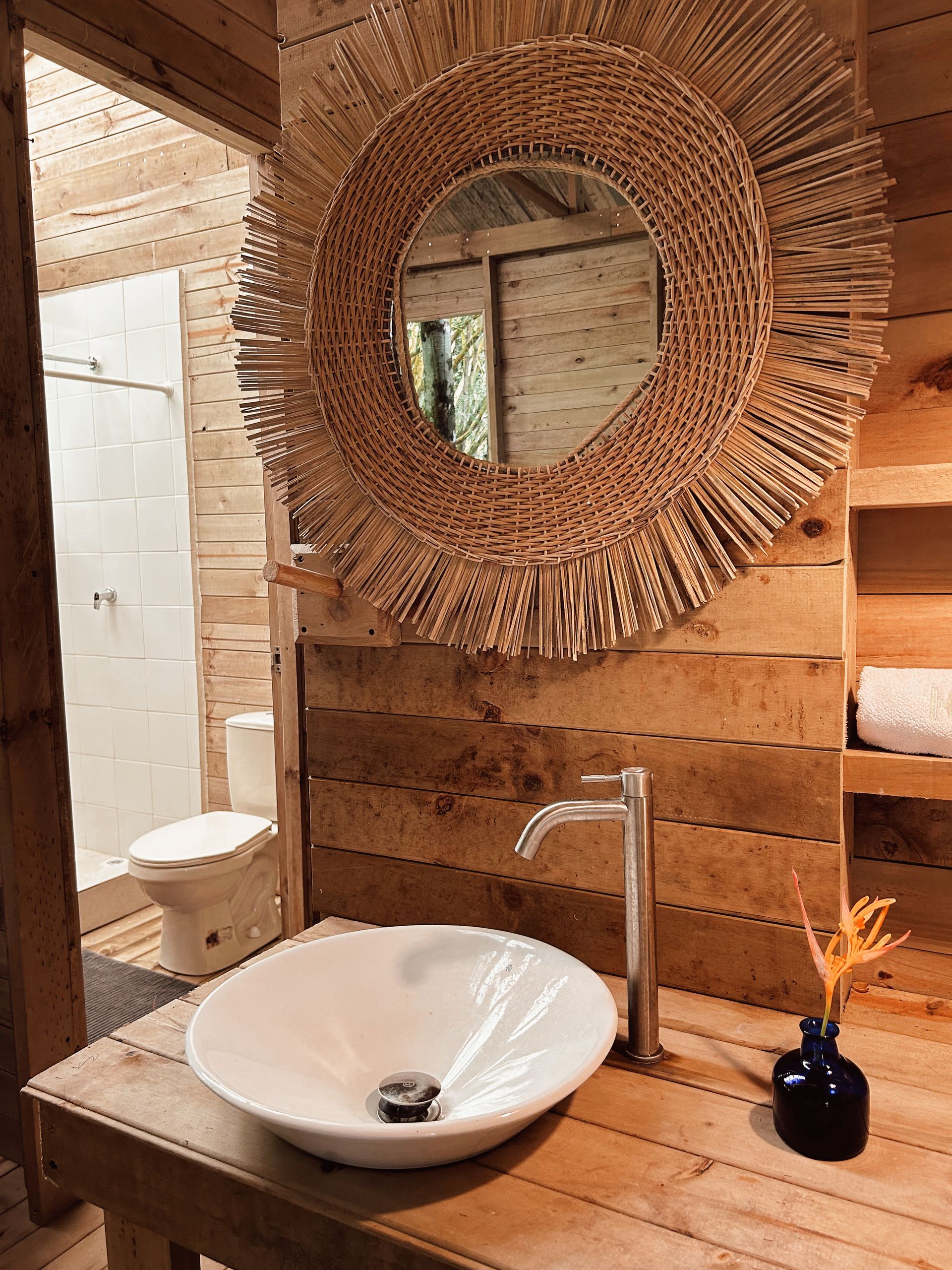 Bathroom with a white sink, decorative mirror, and wooden walls.