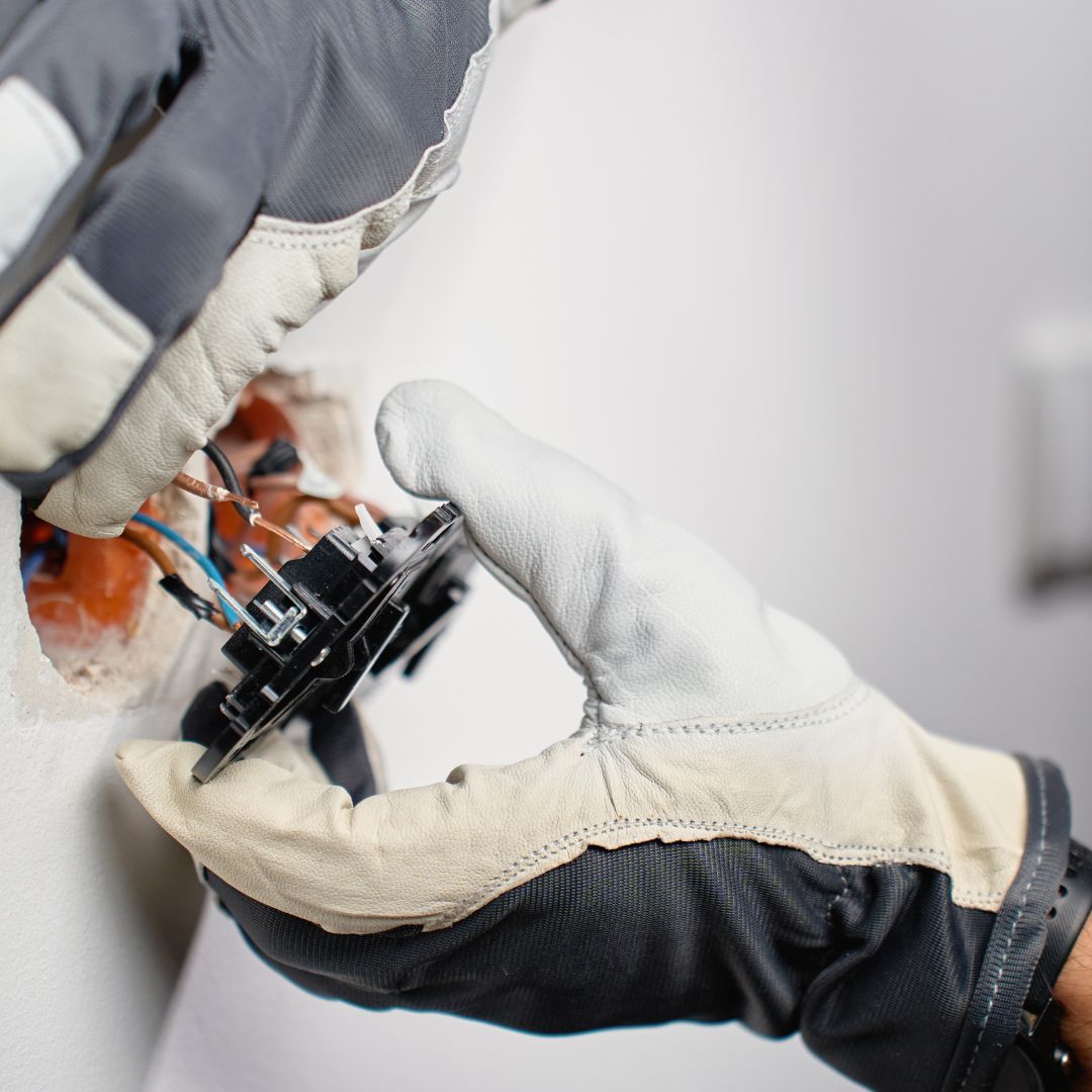 Gloved hands adjusting a black mechanical component on a workbench