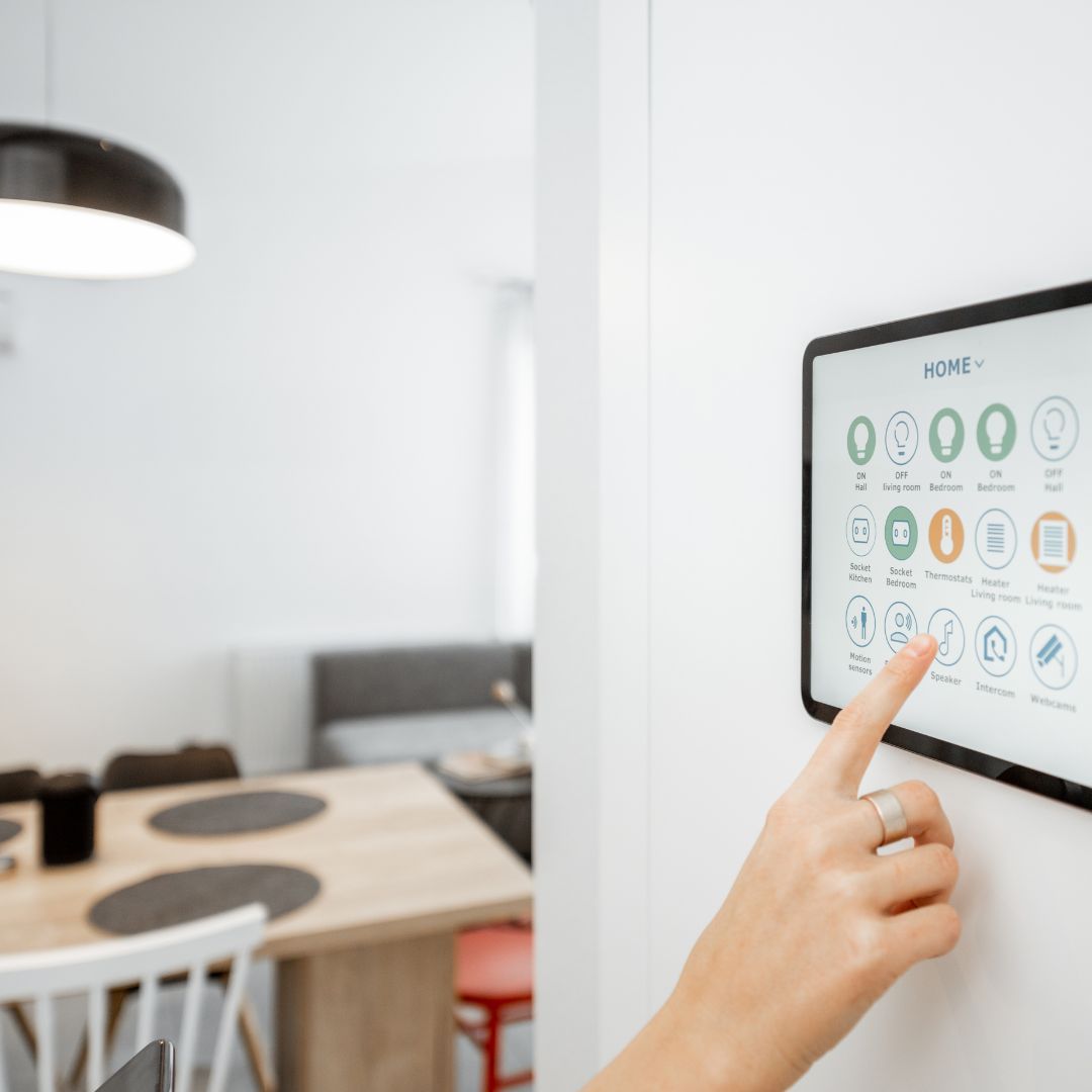 Hand pointing at a wall-mounted touchscreen dashboard in a bright office