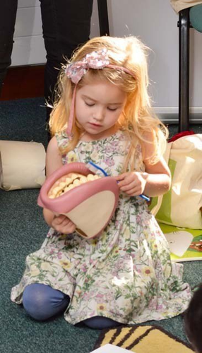 girl practising brushing teeth on a hand puppet mouth