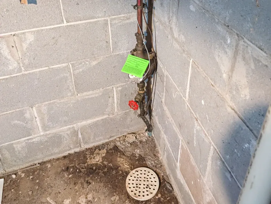 A brick wall with a drain and a valve on it