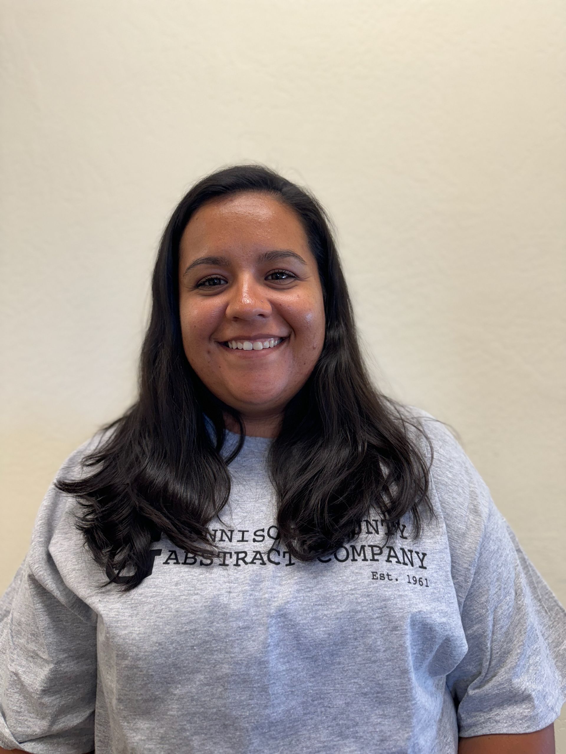 A woman wearing a grey t-shirt is smiling for the camera.