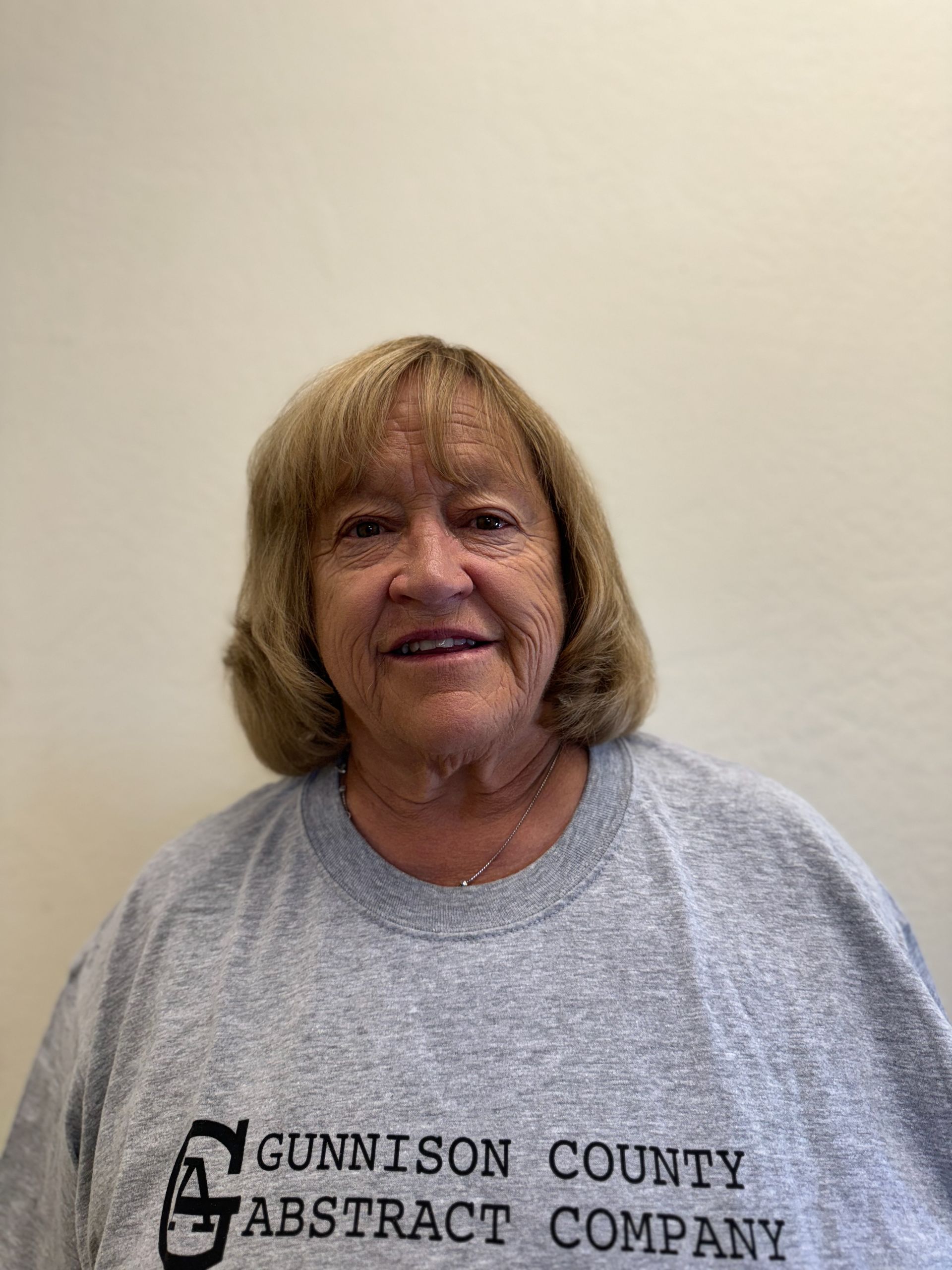 A woman is wearing a gunnison county abstract company t-shirt.
