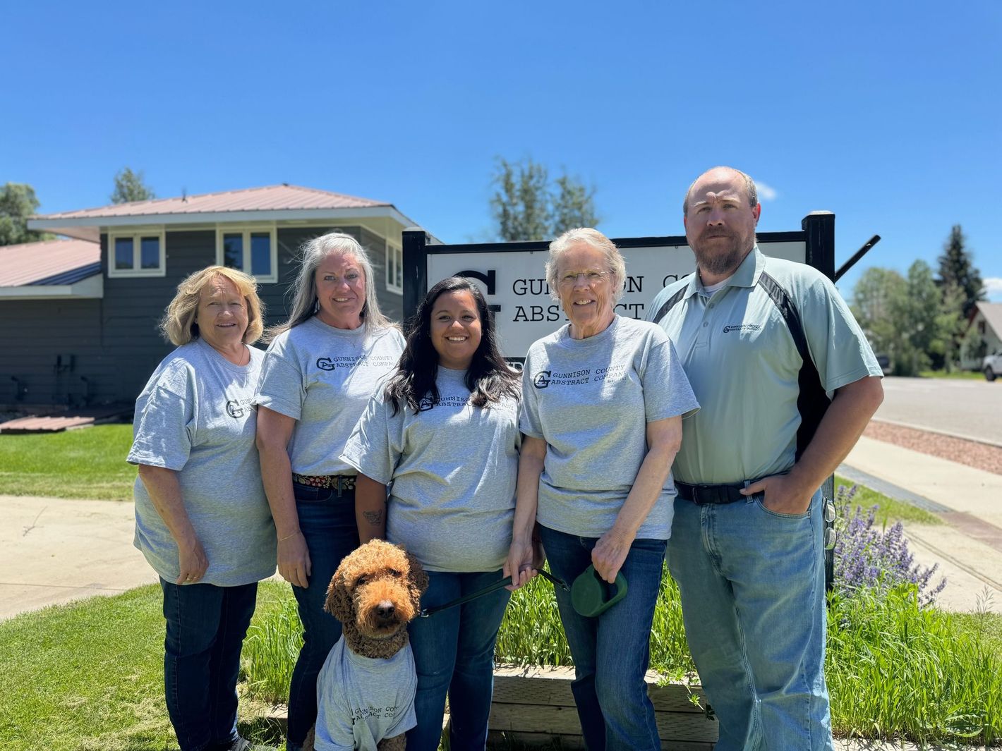 A group of people and a dog are posing for a picture in front of a building.