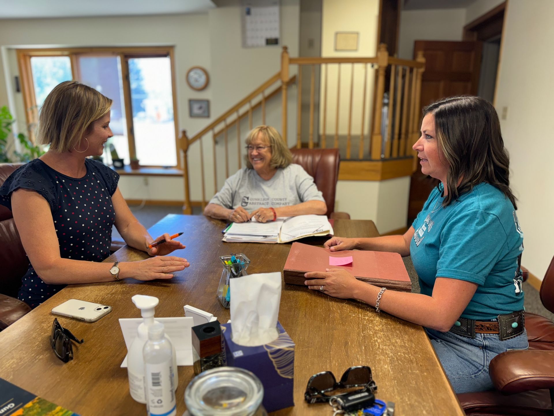 Three women are sitting at a table talking to each other.