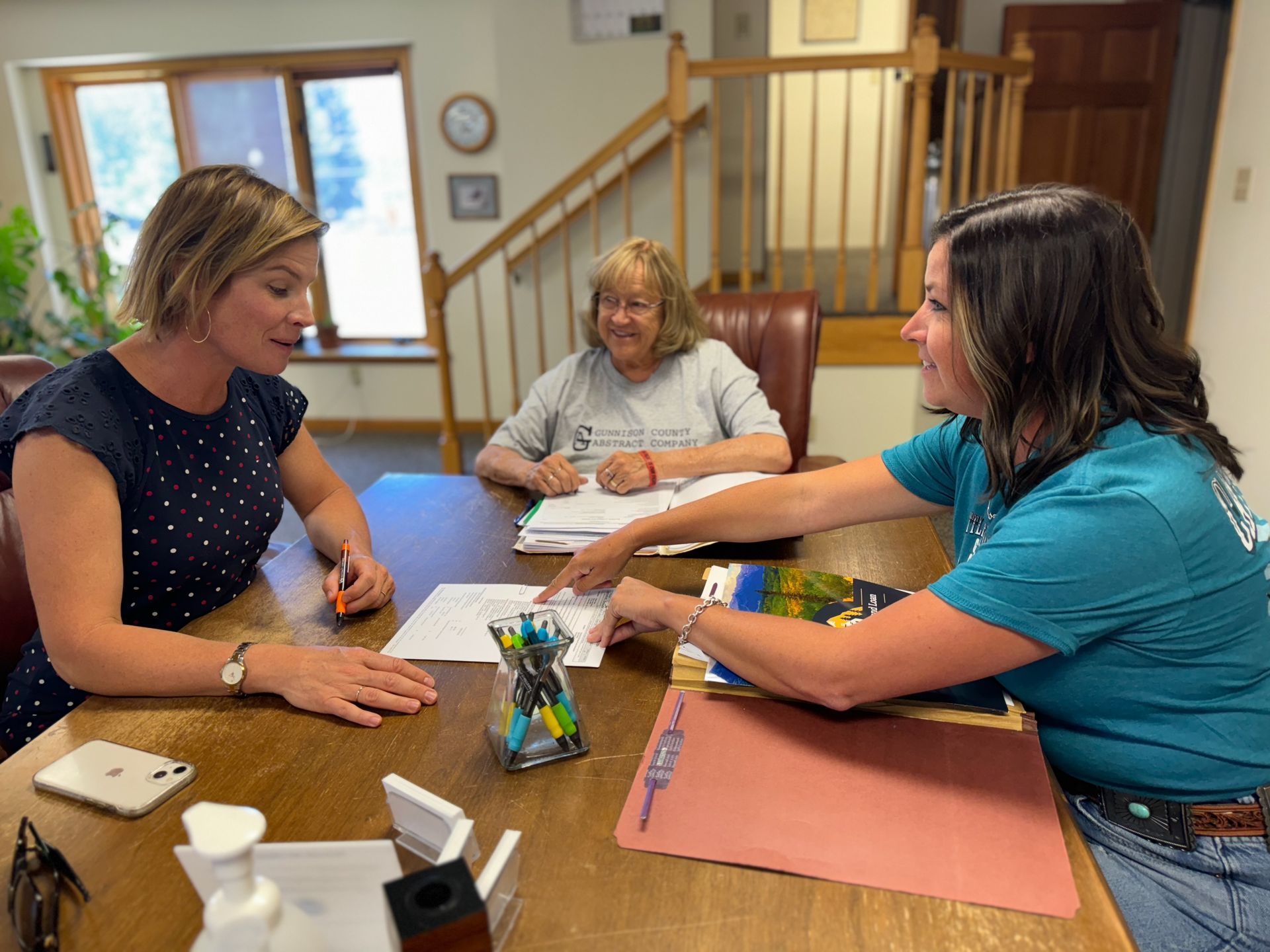 Three women are sitting at a table talking to each other.