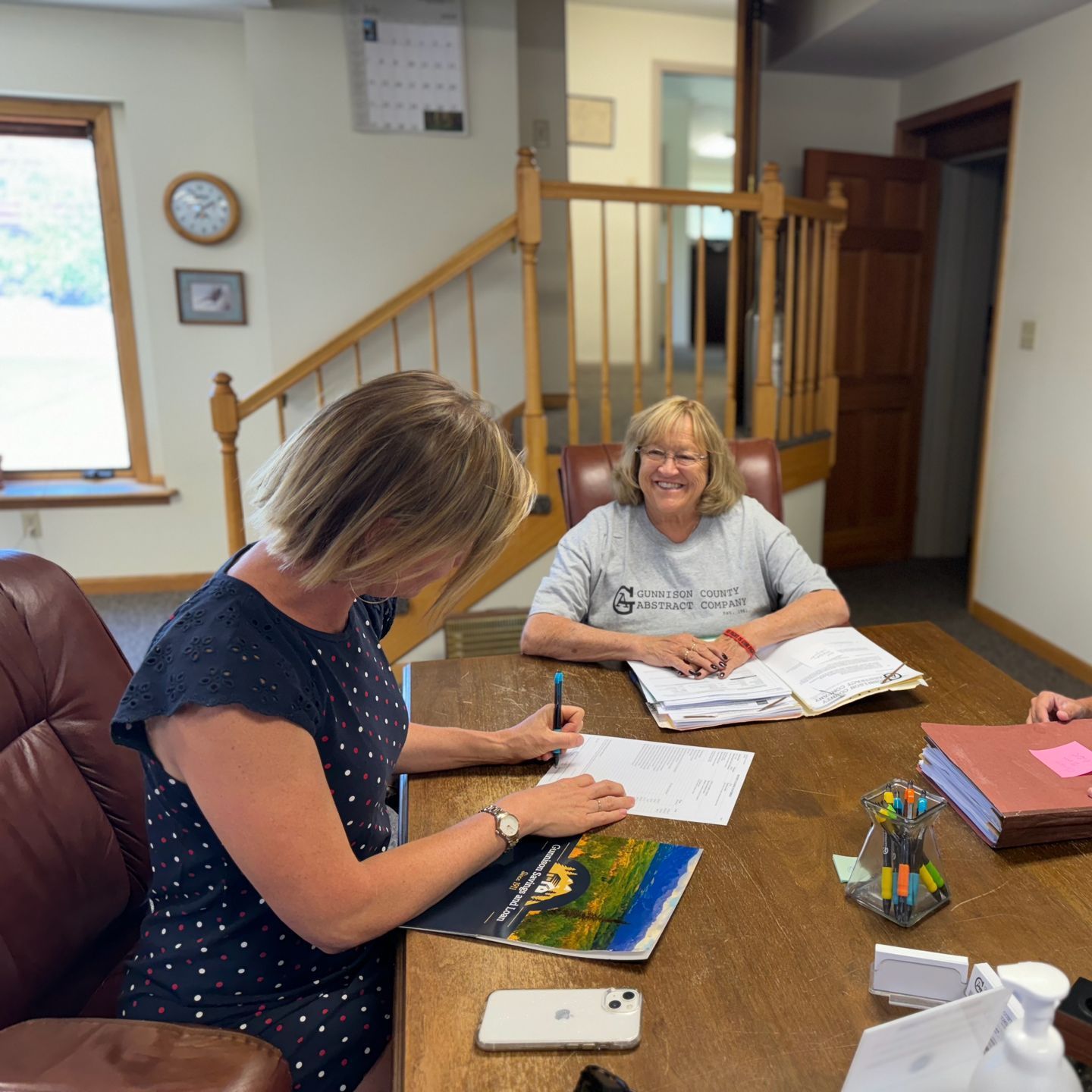 A group of women are sitting around a table writing on papers