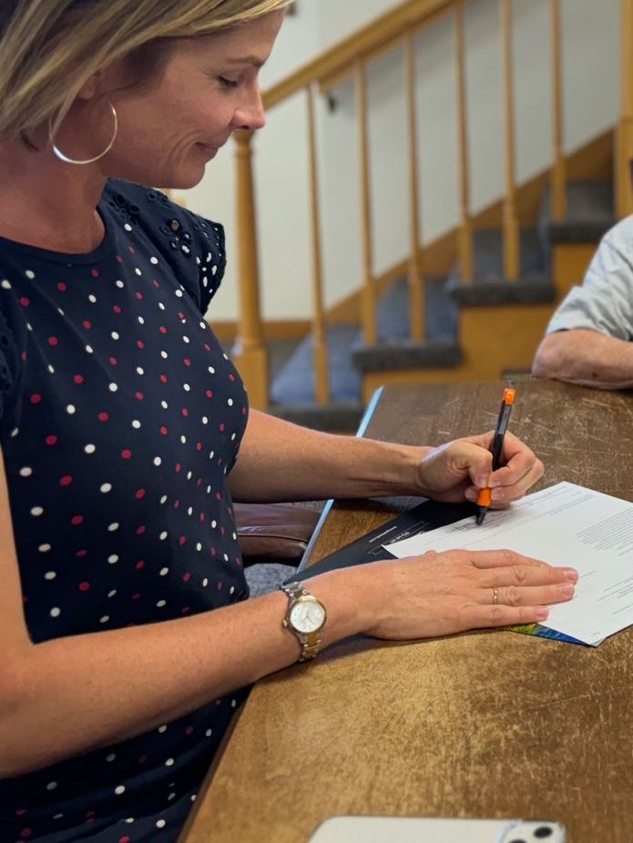 A woman is writing on a piece of paper with a pen.