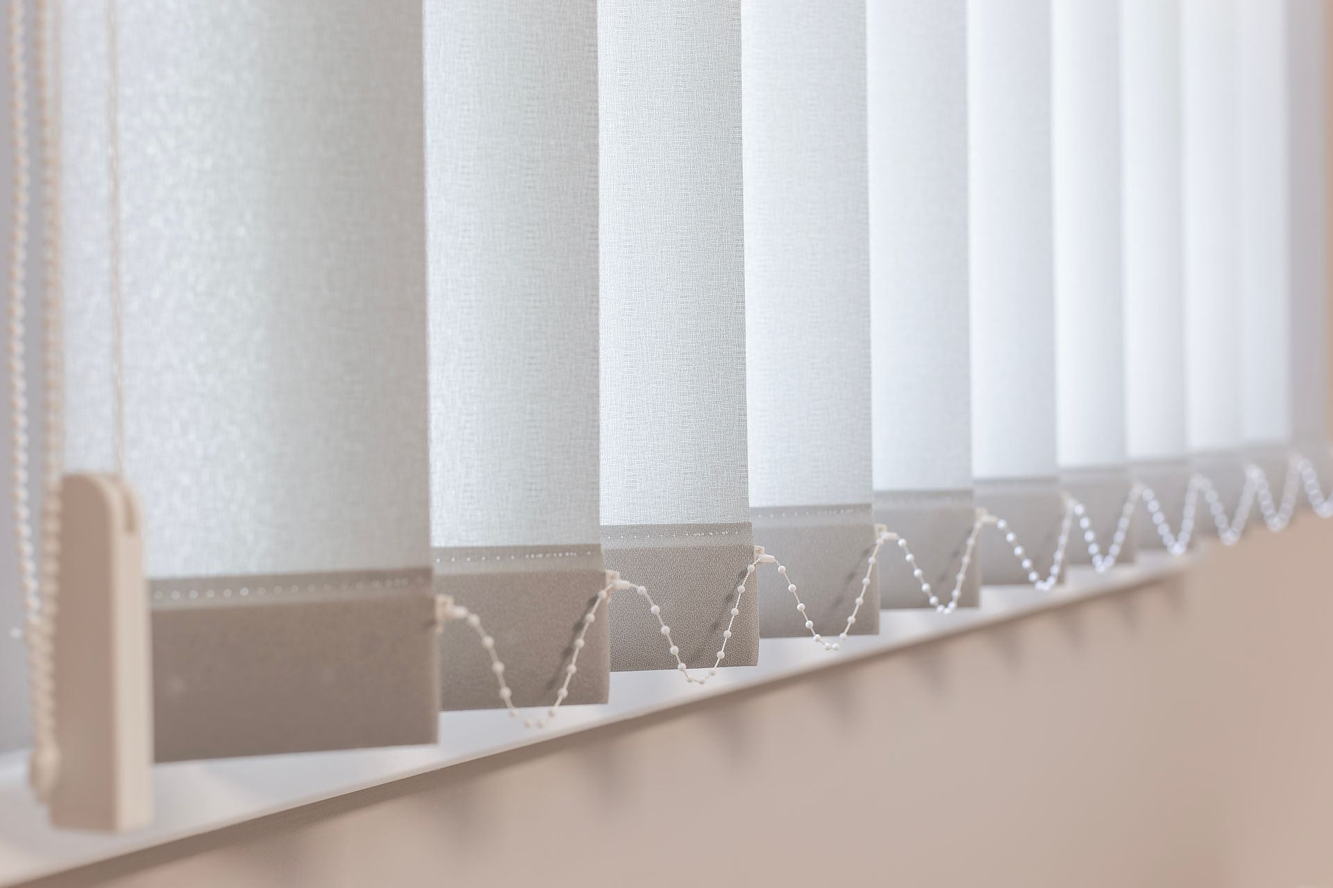 White vertical blinds, partially open, casting shadows.