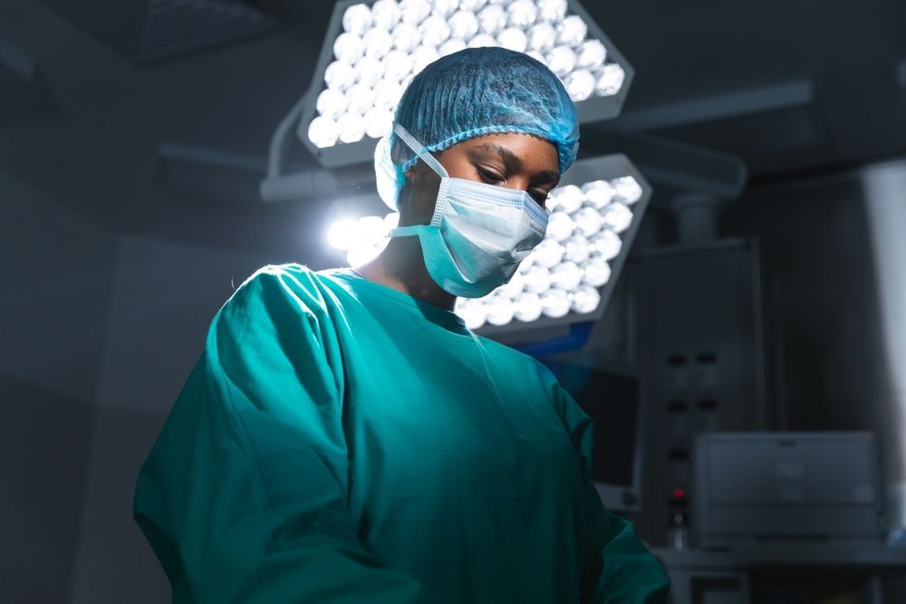 A surgeon wearing a mask and gown is standing in an operating room.