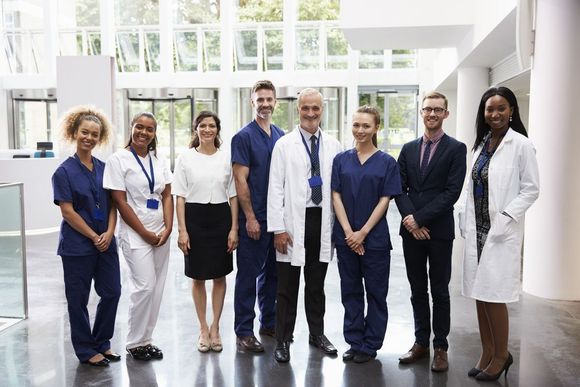 A group of doctors and nurses are posing for a picture in a hospital hallway.