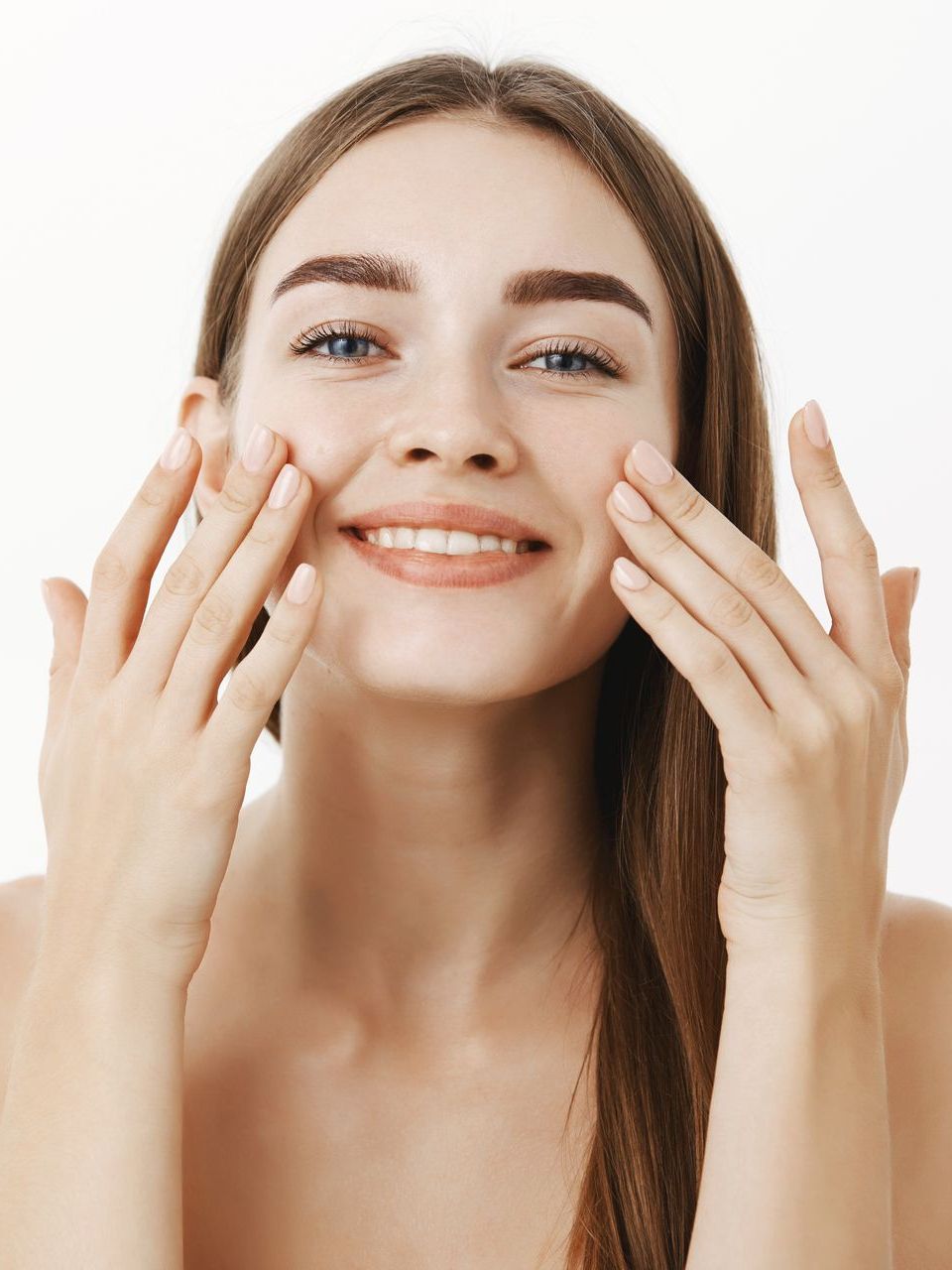 a woman is smiling and touching her face with her hands