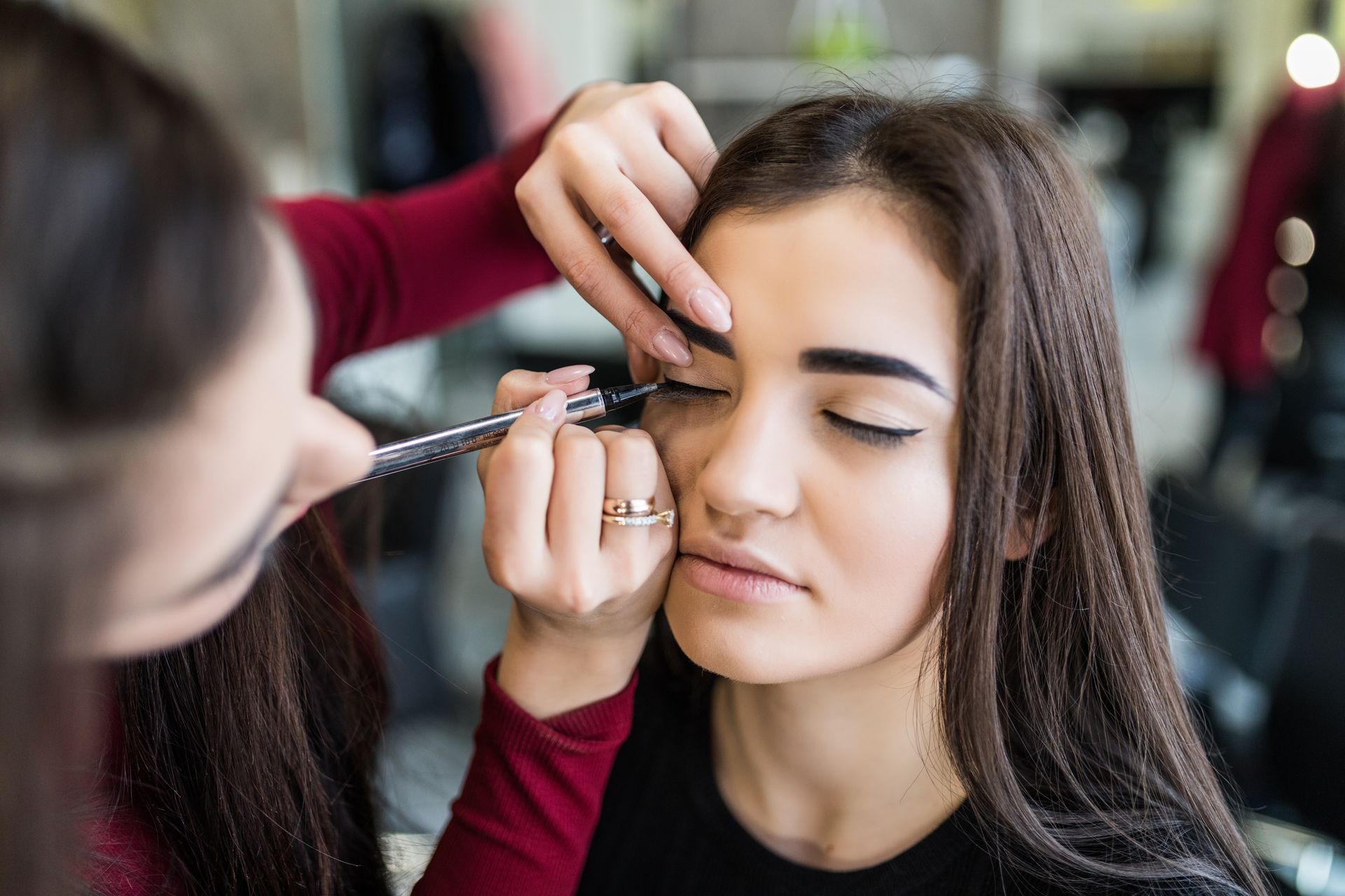 a woman is applying eyeliner to another woman 's eye