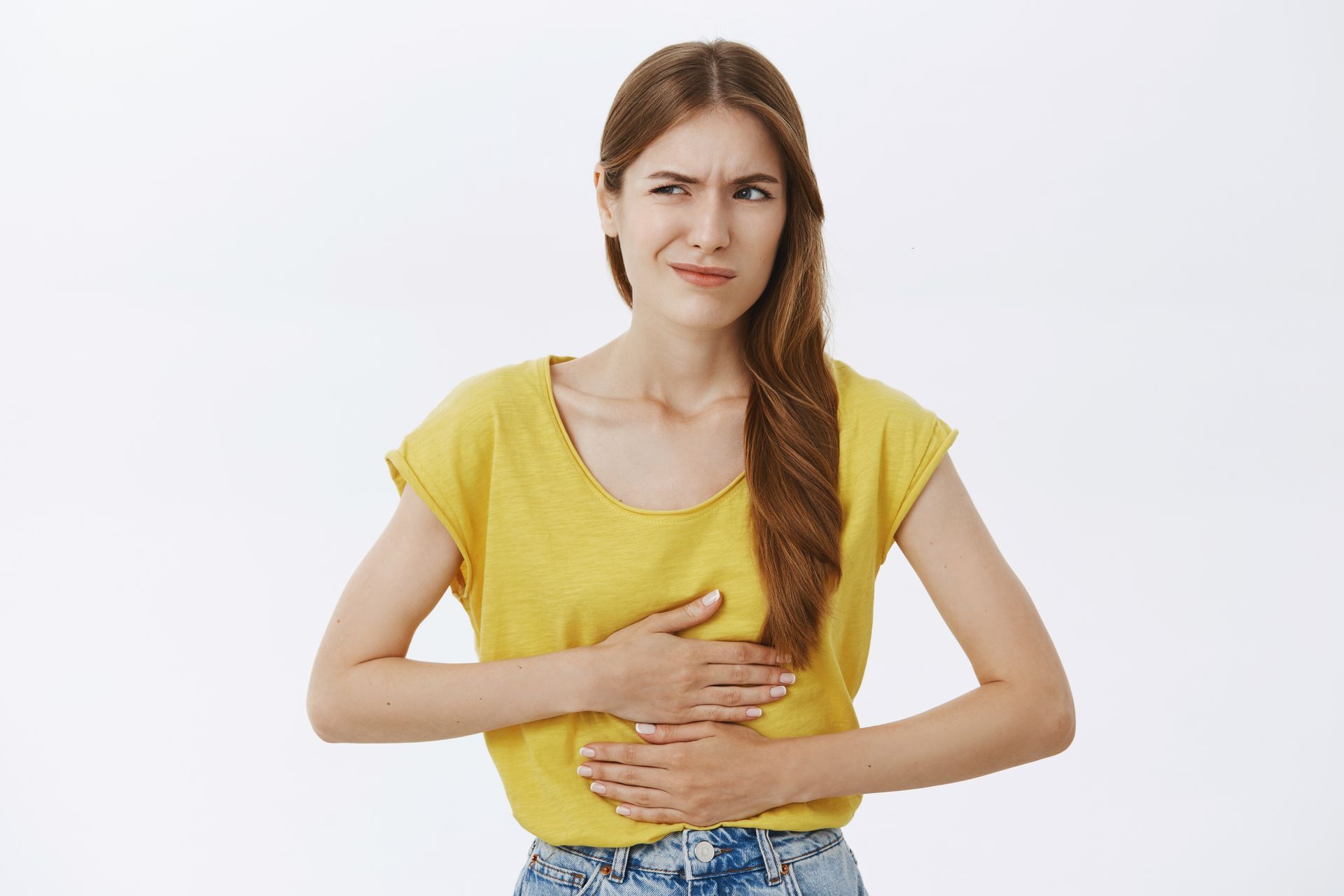 a woman in a yellow shirt is holding her stomach