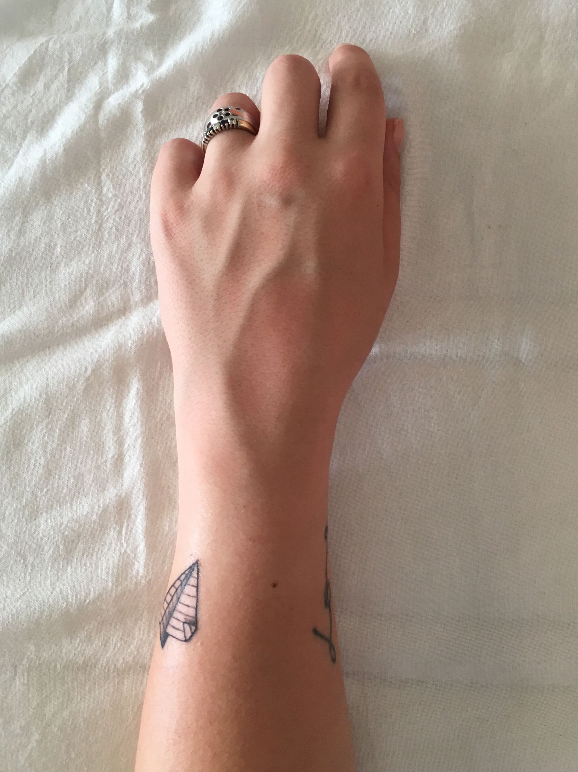 a woman 's wrist has a small tattoo of a sailboat on it