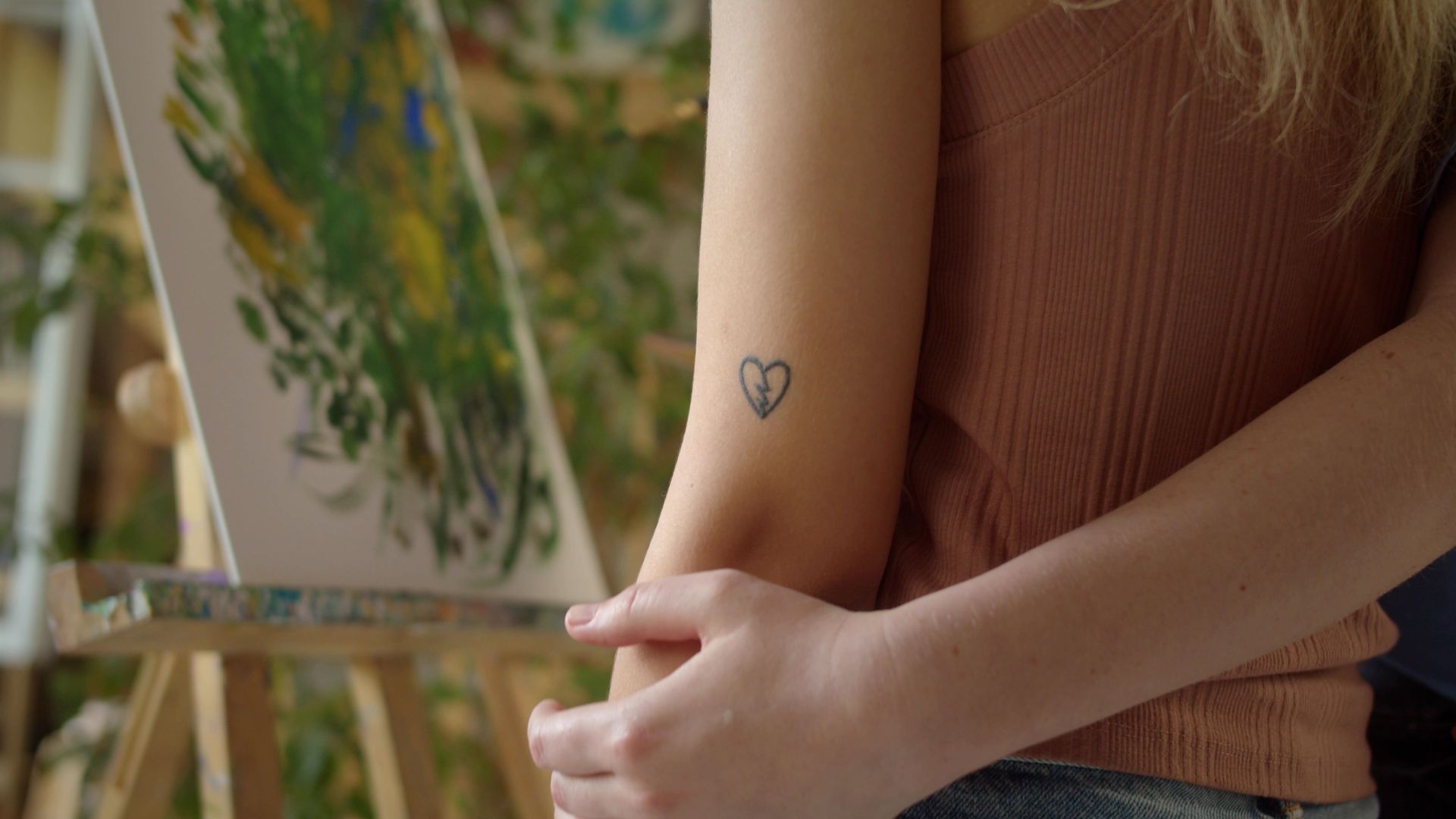 a woman has a small heart tattoo on her arm