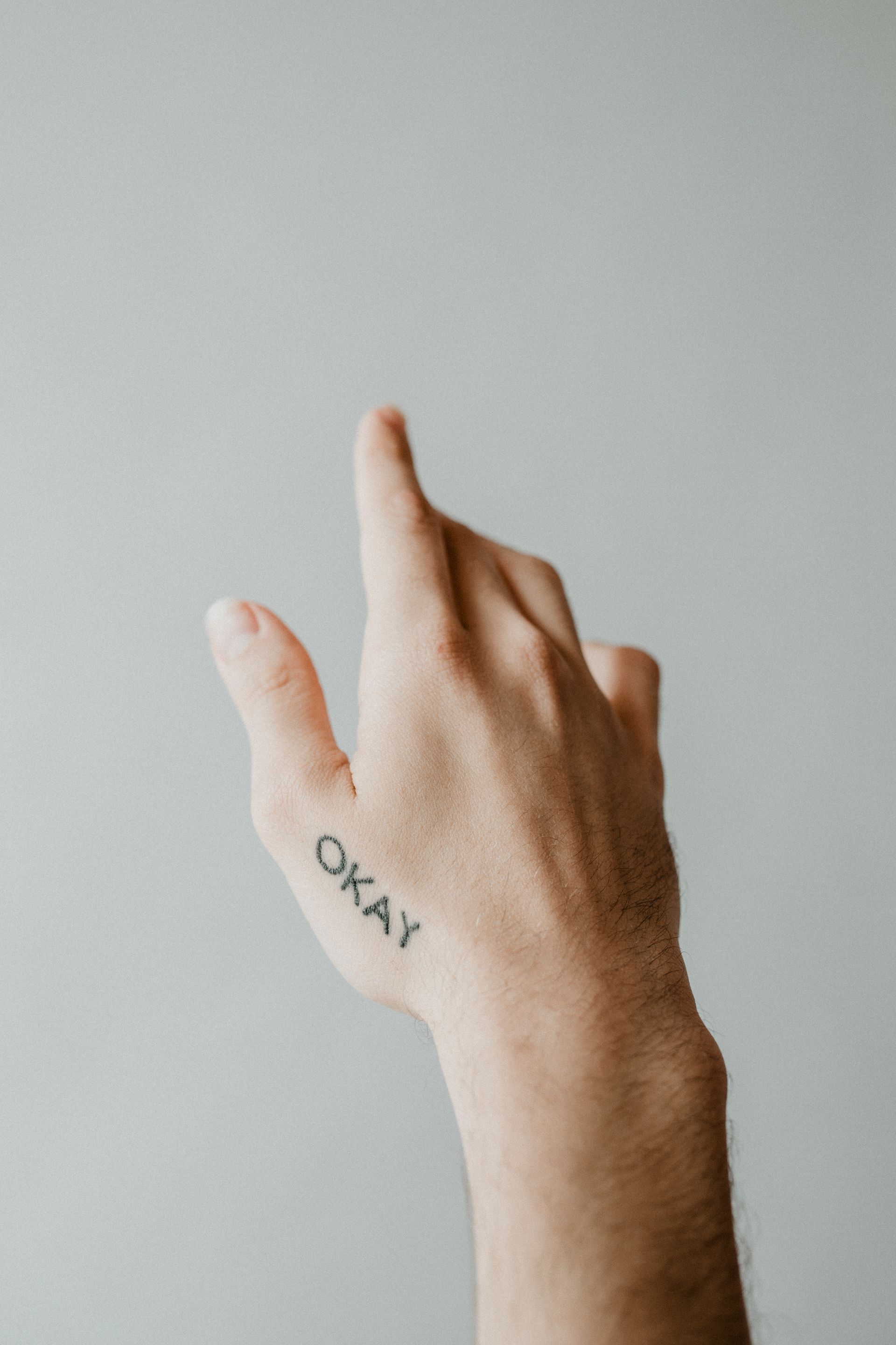 a hand with the word okay tattooed on it