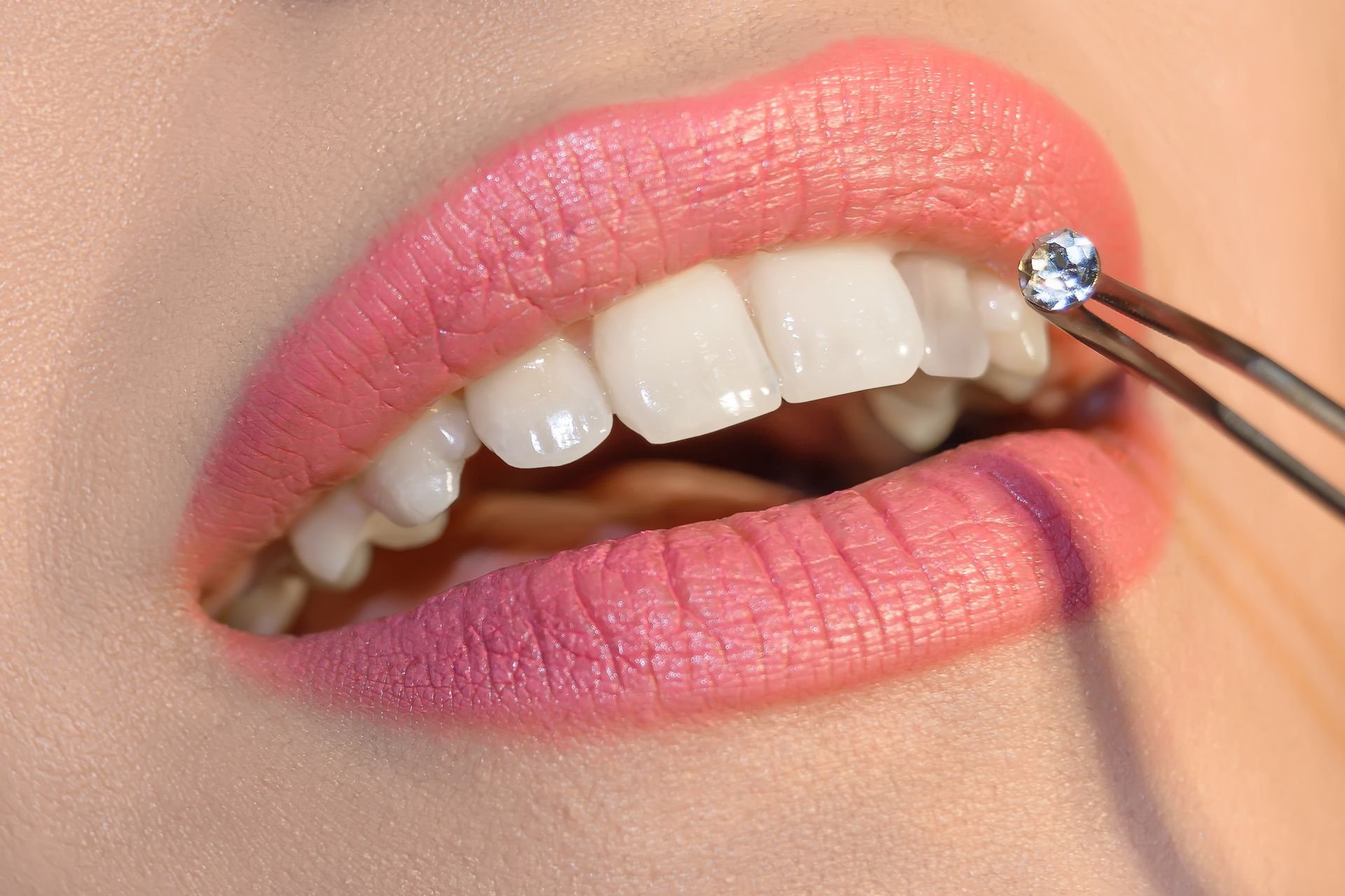 a woman with pink lips has a diamond in her mouth