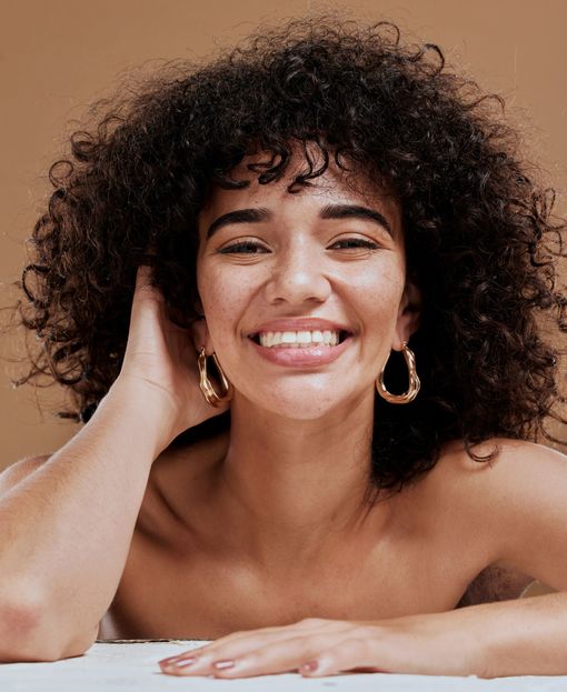 a woman with curly hair wearing hoop earrings is smiling