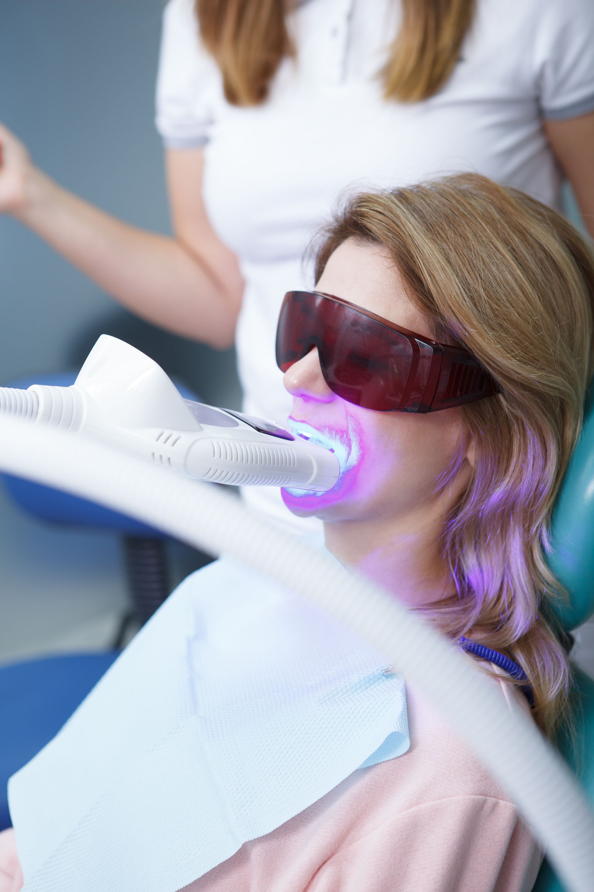 a woman is getting her teeth whitened by a dentist