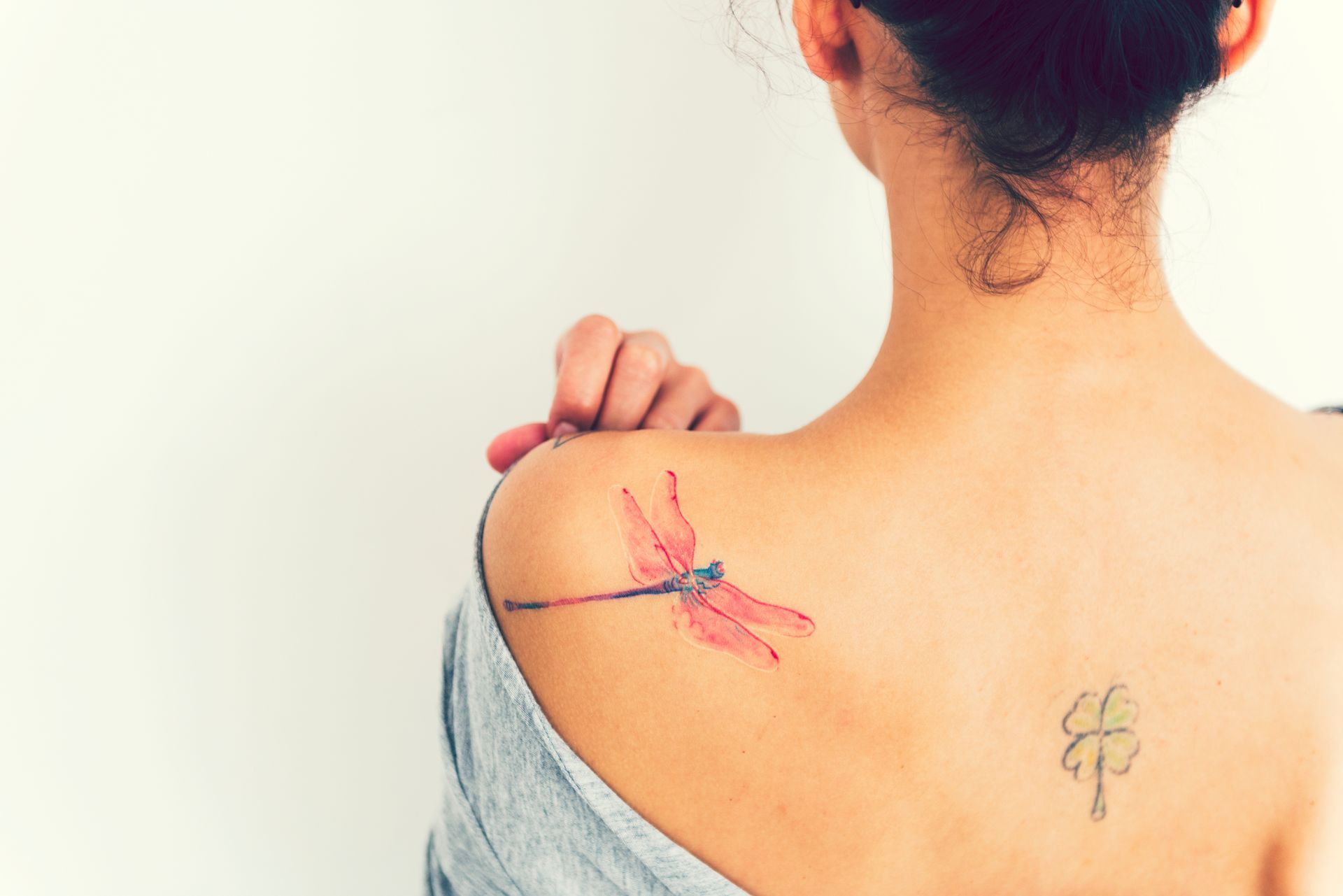 a woman has a dragonfly tattoo on her back