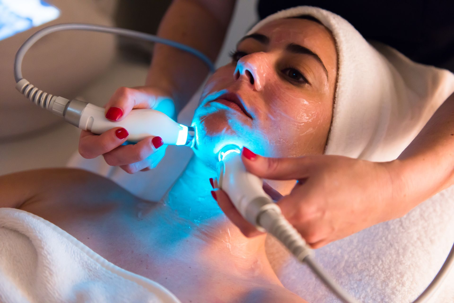 a woman is getting a blue light treatment on her face