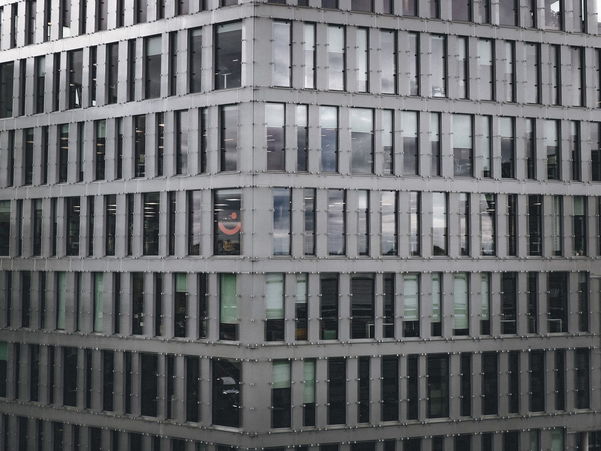 Modern office building facade with rows of windows and gray metal panels