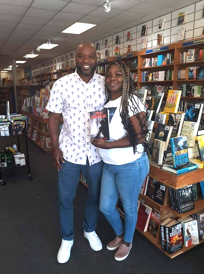 A man and a woman are posing for a picture in a bookstore.