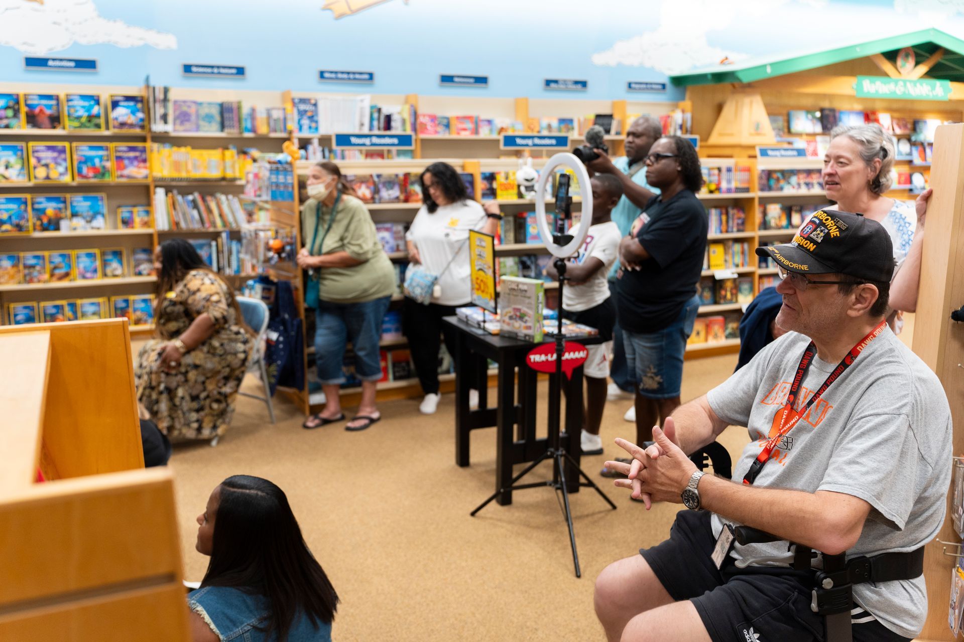 A group of people are sitting in a library watching a presentation.