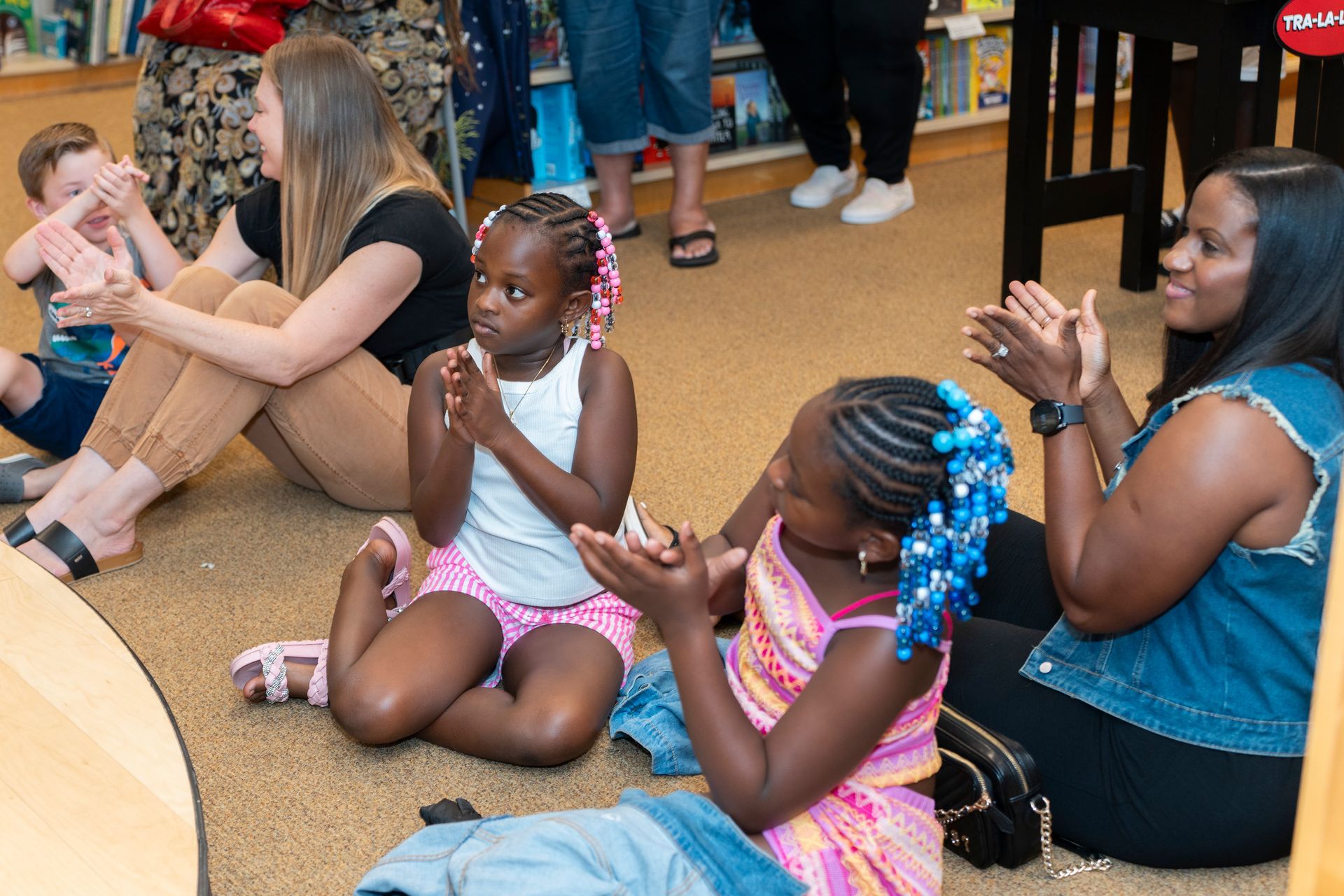 A group of young girls are sitting on the floor clapping their hands.