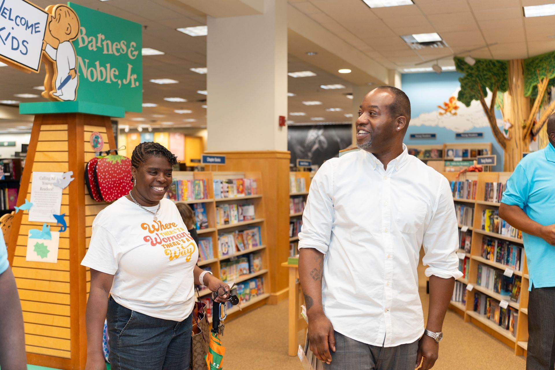 A man and a woman are standing in a bookstore talking to each other
