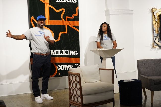 A man and a woman are standing in front of a sign that says milking cows.