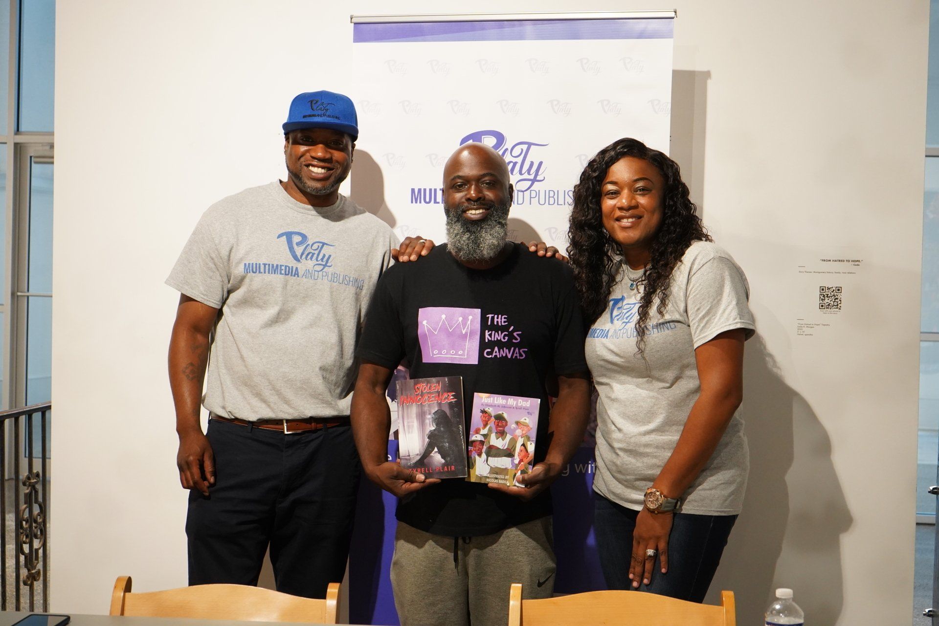 A man and two women are standing next to each other holding books.