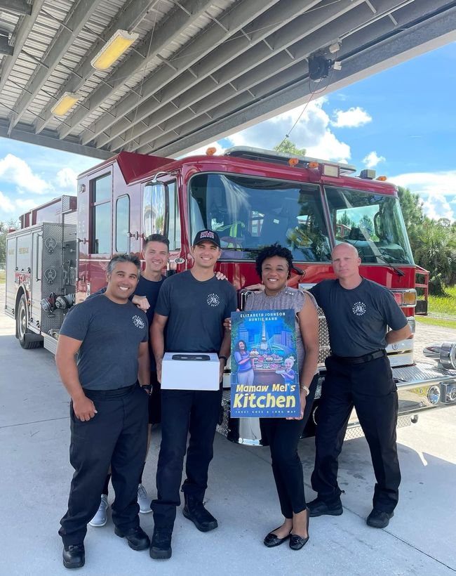 A group of firefighters are posing for a picture in front of a fire truck.