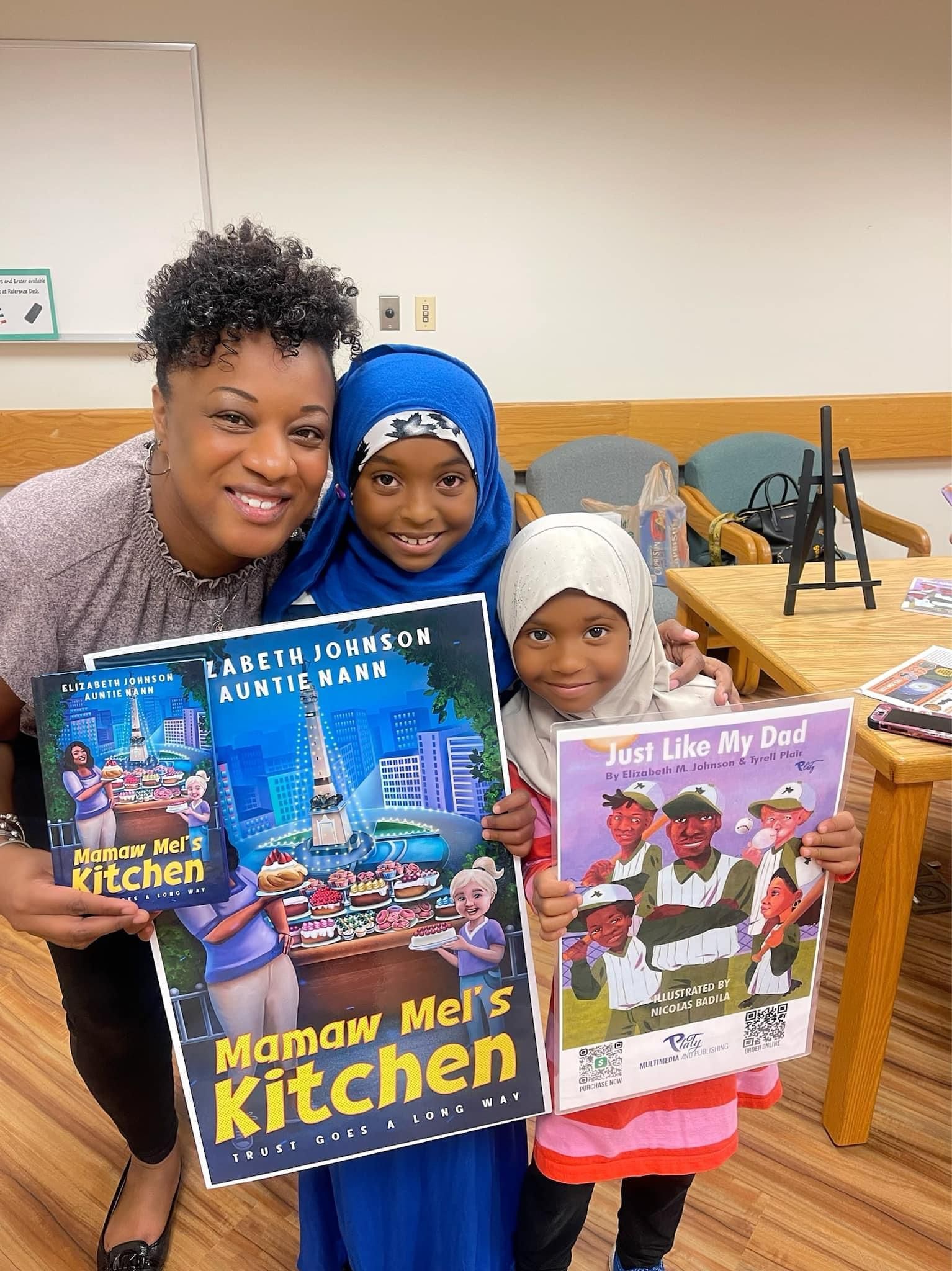 A woman and two children are holding books in a classroom.