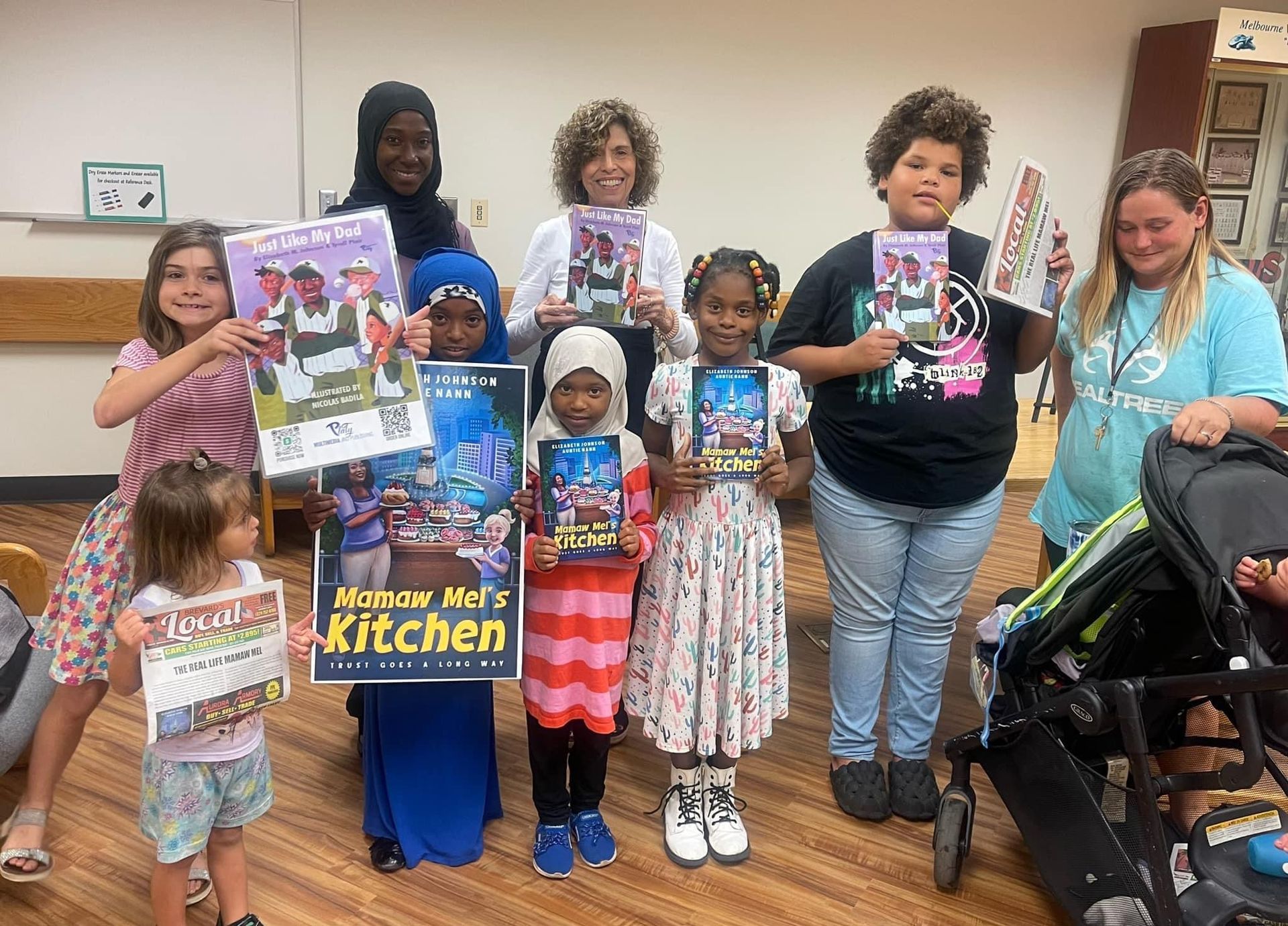 A group of children are standing next to each other holding books and signs.