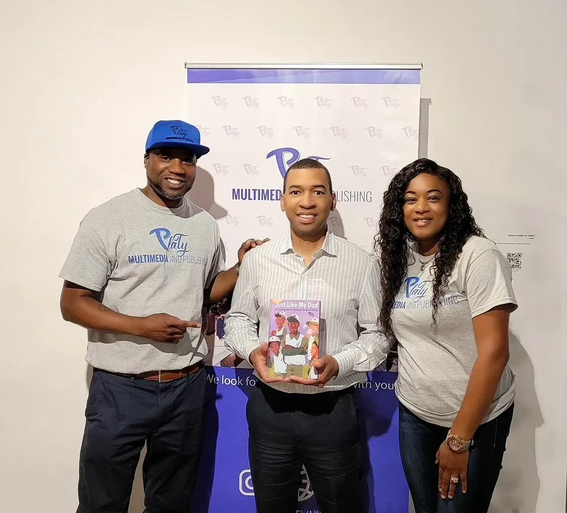 Three people are posing for a picture in front of a banner.