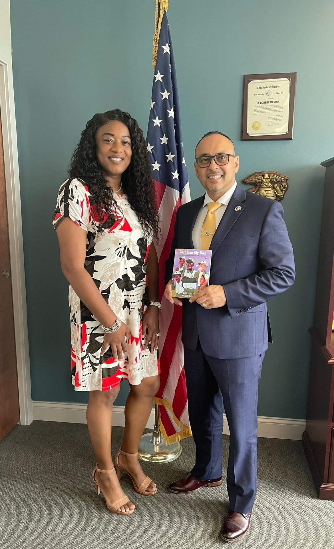 A man and a woman are standing next to each other in front of an american flag.