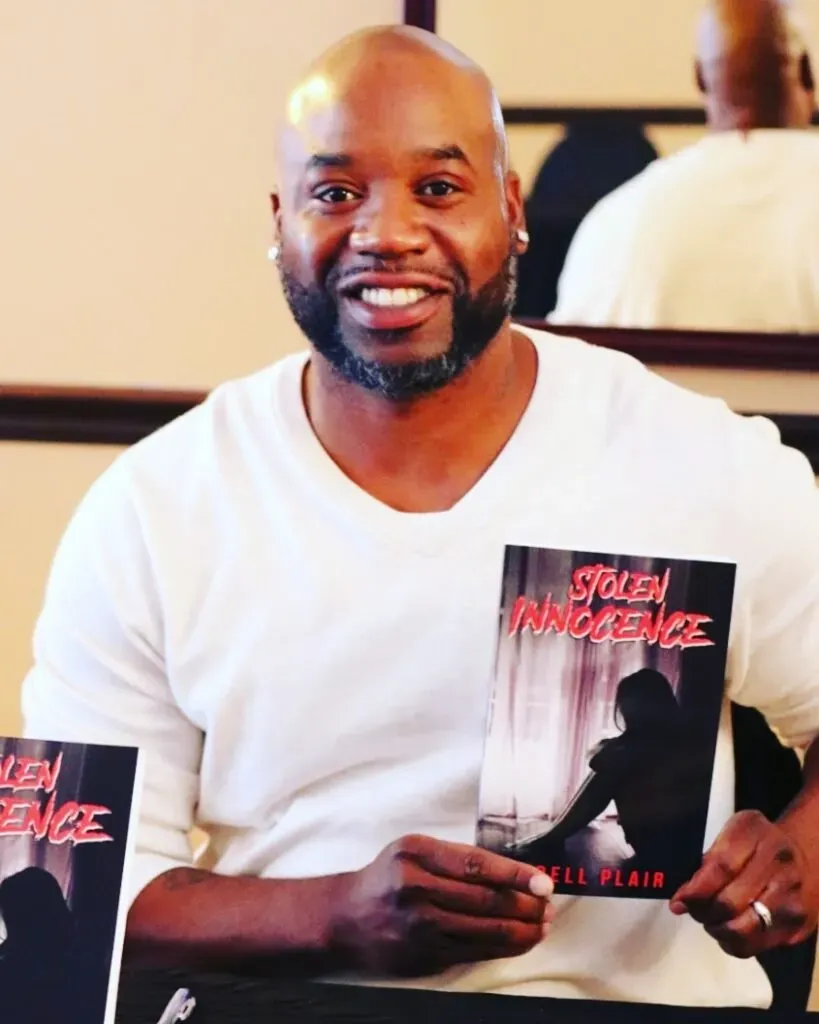 A man in a white shirt is holding a book titled stolen innocence