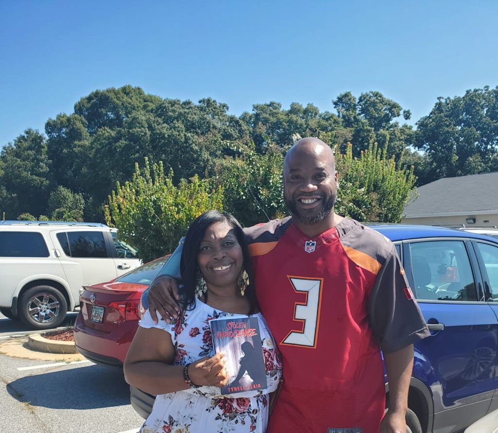 A man and a woman are posing for a picture in a parking lot