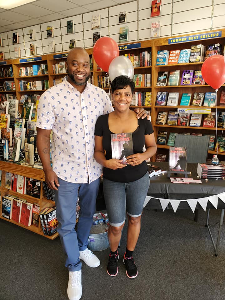 A man and a woman are posing for a picture in a bookstore.