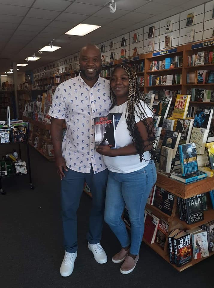 A man and a woman are posing for a picture in a bookstore.