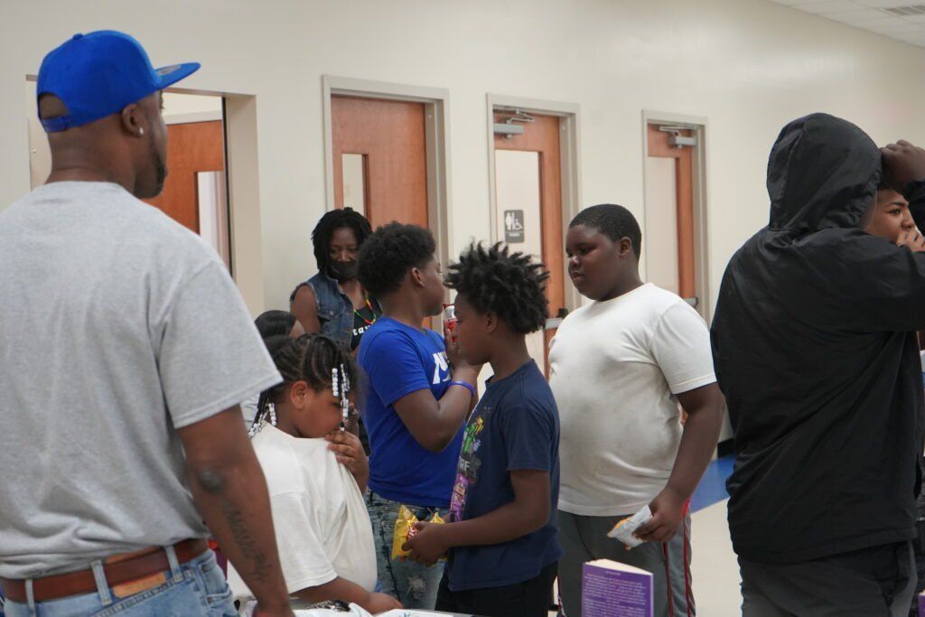 A group of people are standing in a room talking to each other
