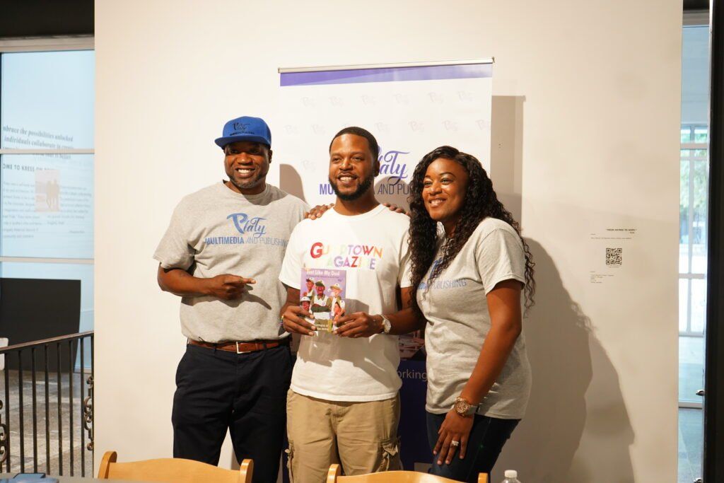 Three people are posing for a picture in front of a wall.
