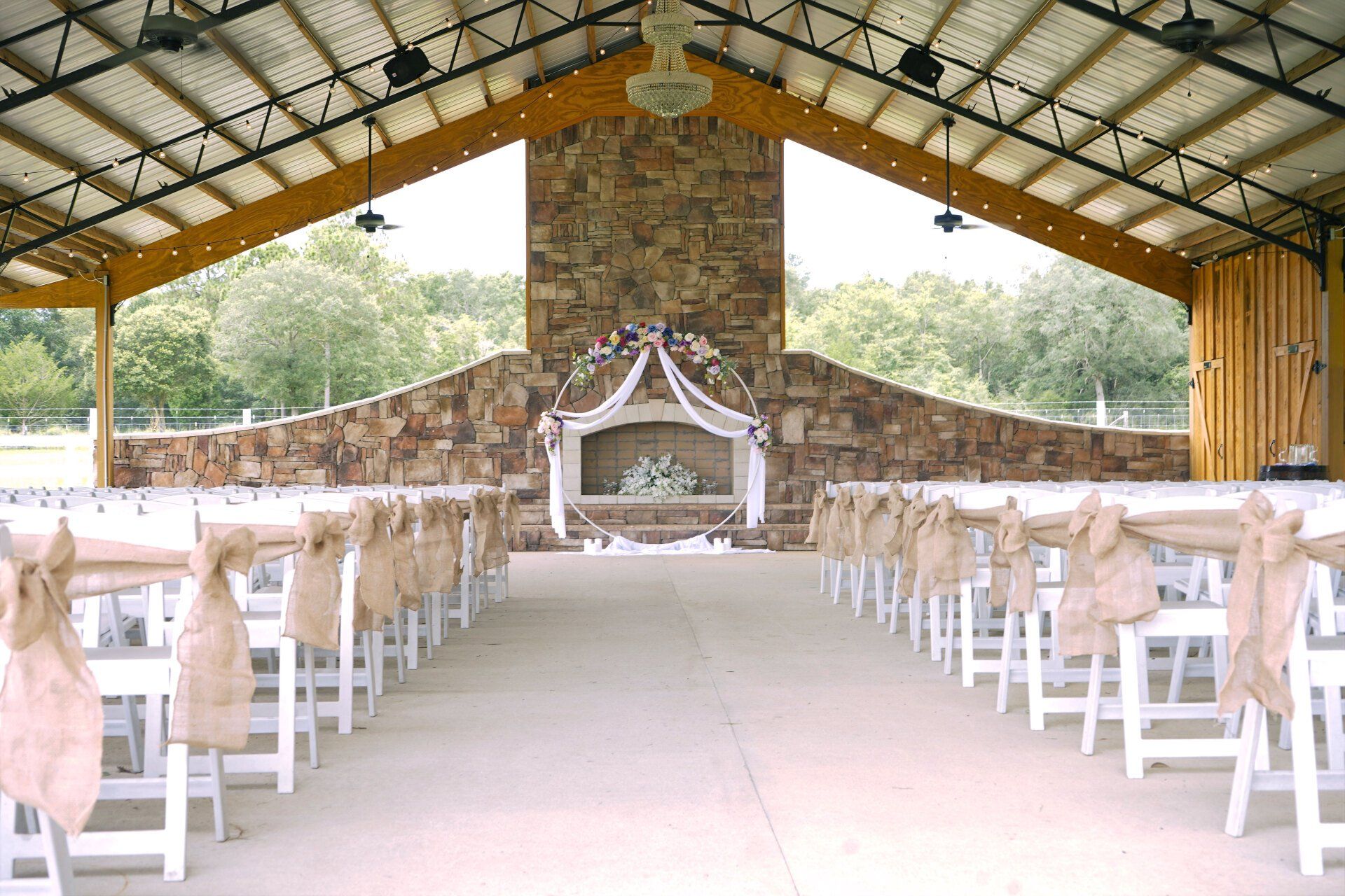 A row of white folding chairs are lined up in front of a stone fireplace.