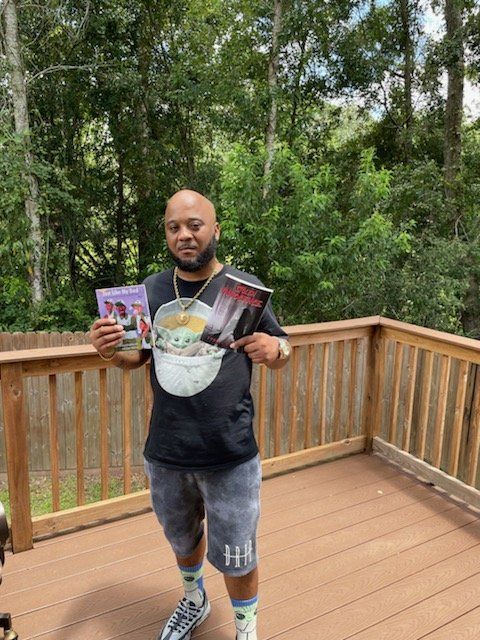 A man is standing on a deck holding two books.