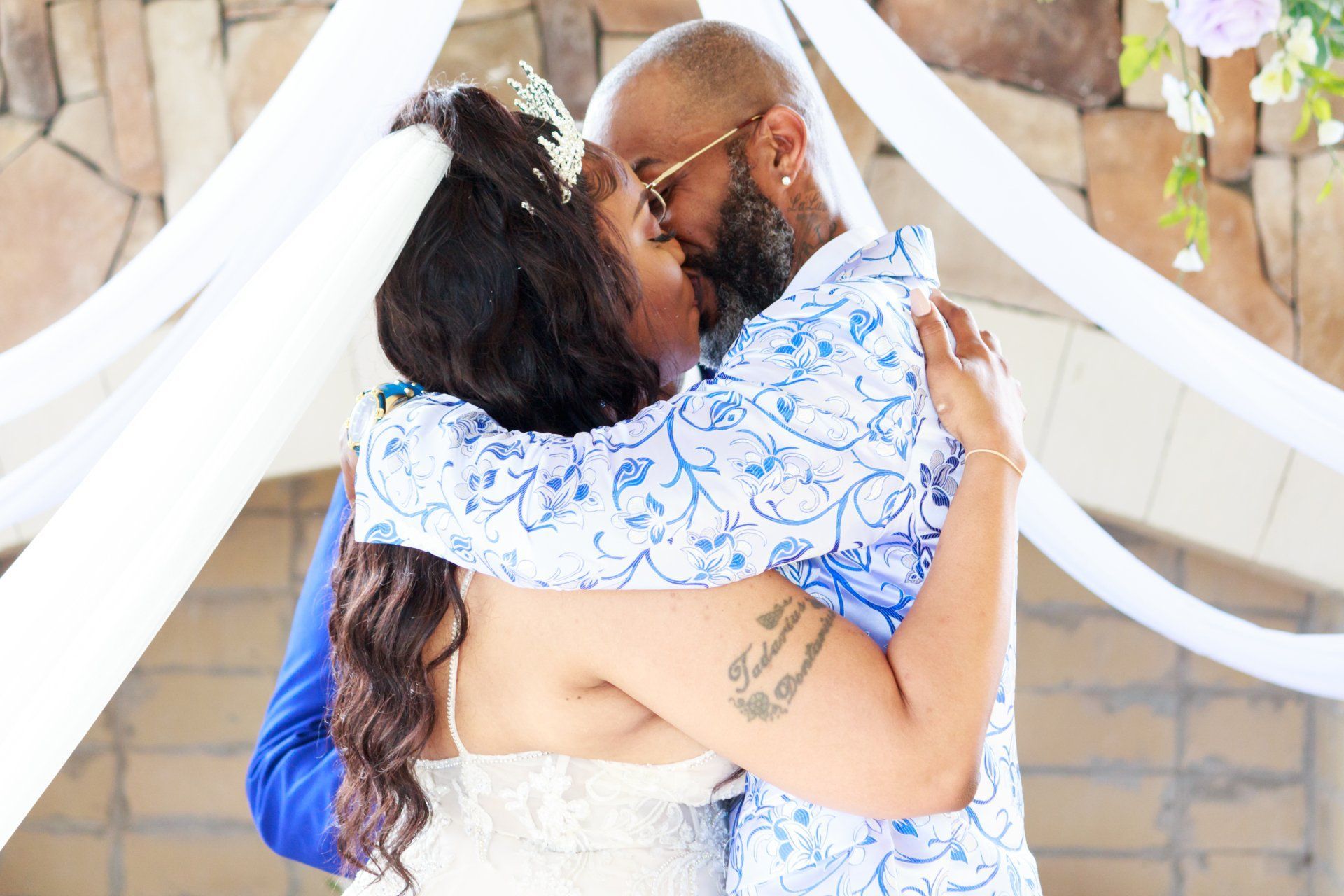A bride and groom are kissing during their wedding ceremony.