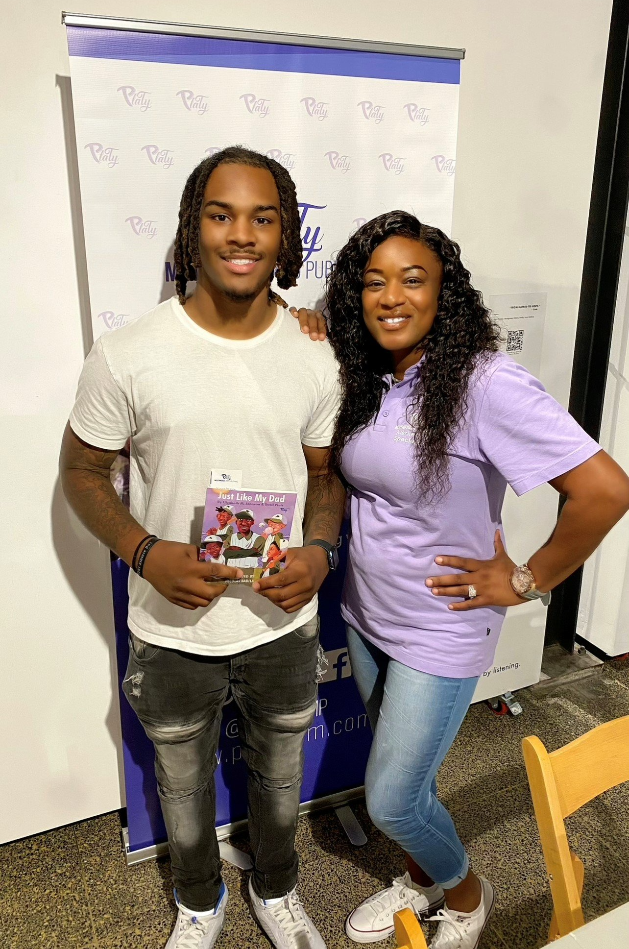 A man and a woman are standing next to each other in a room . the woman is wearing a purple shirt.