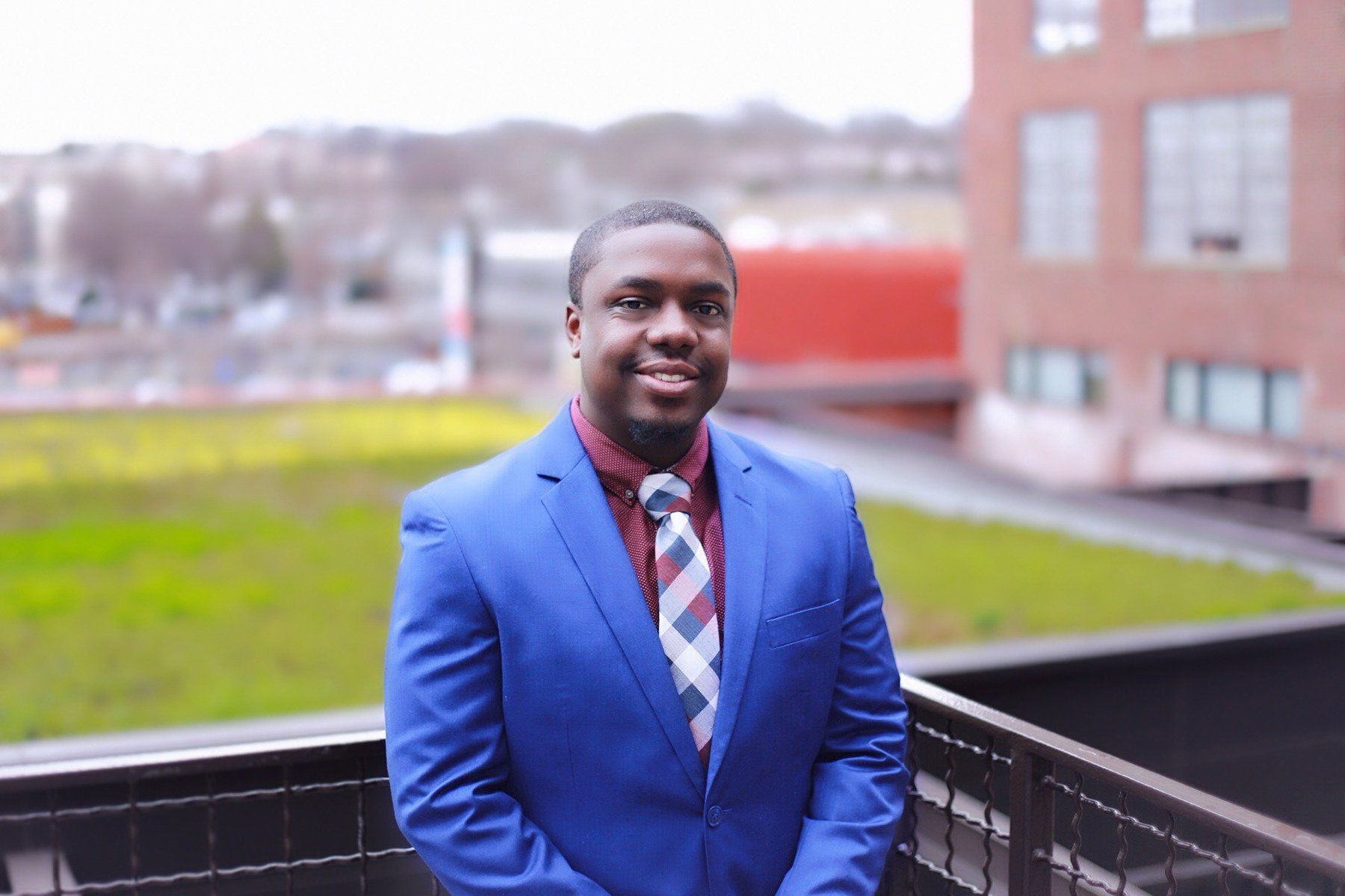 A man in a blue suit and tie is standing on a balcony.